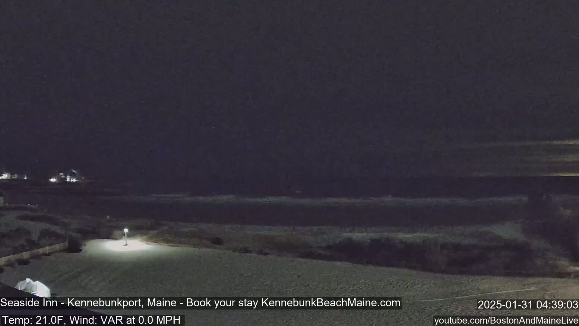 A nighttime view of a dark beach and ocean under a clear, dark sky.