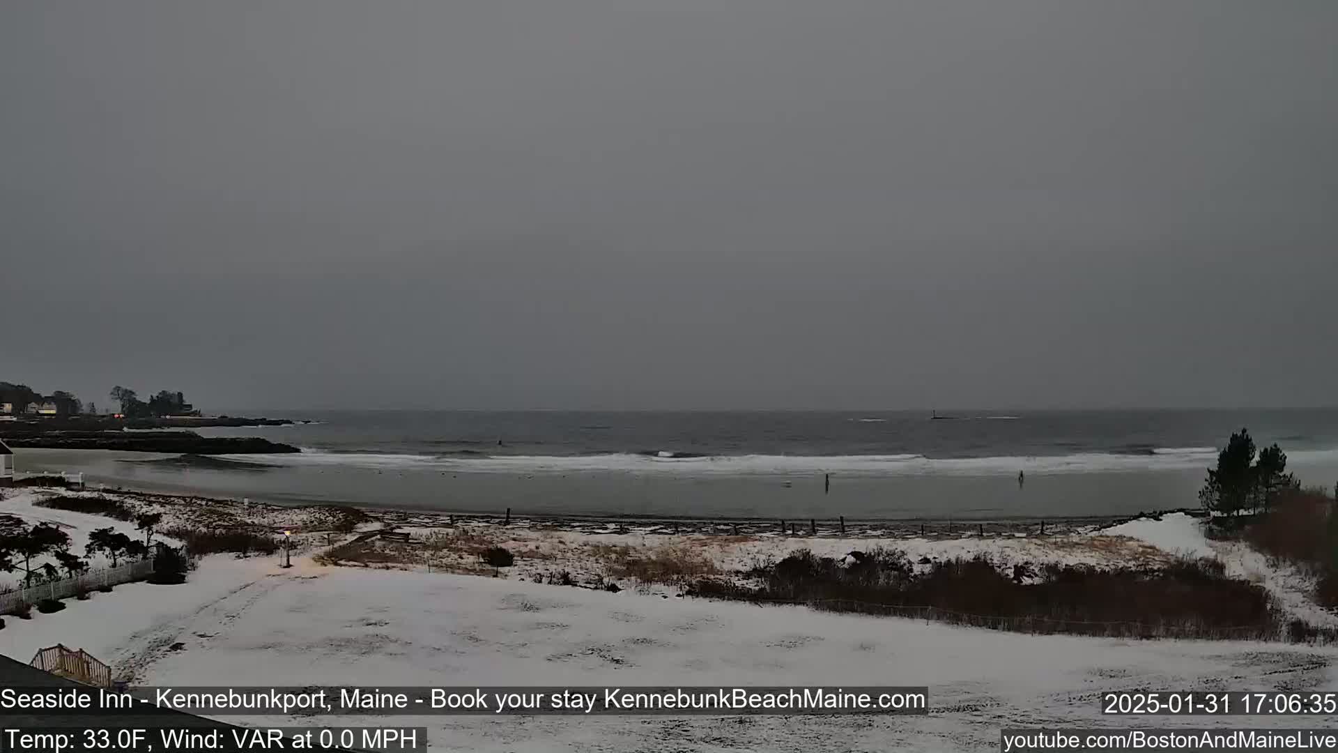 A snow-covered beach and ocean are visible under an overcast sky.