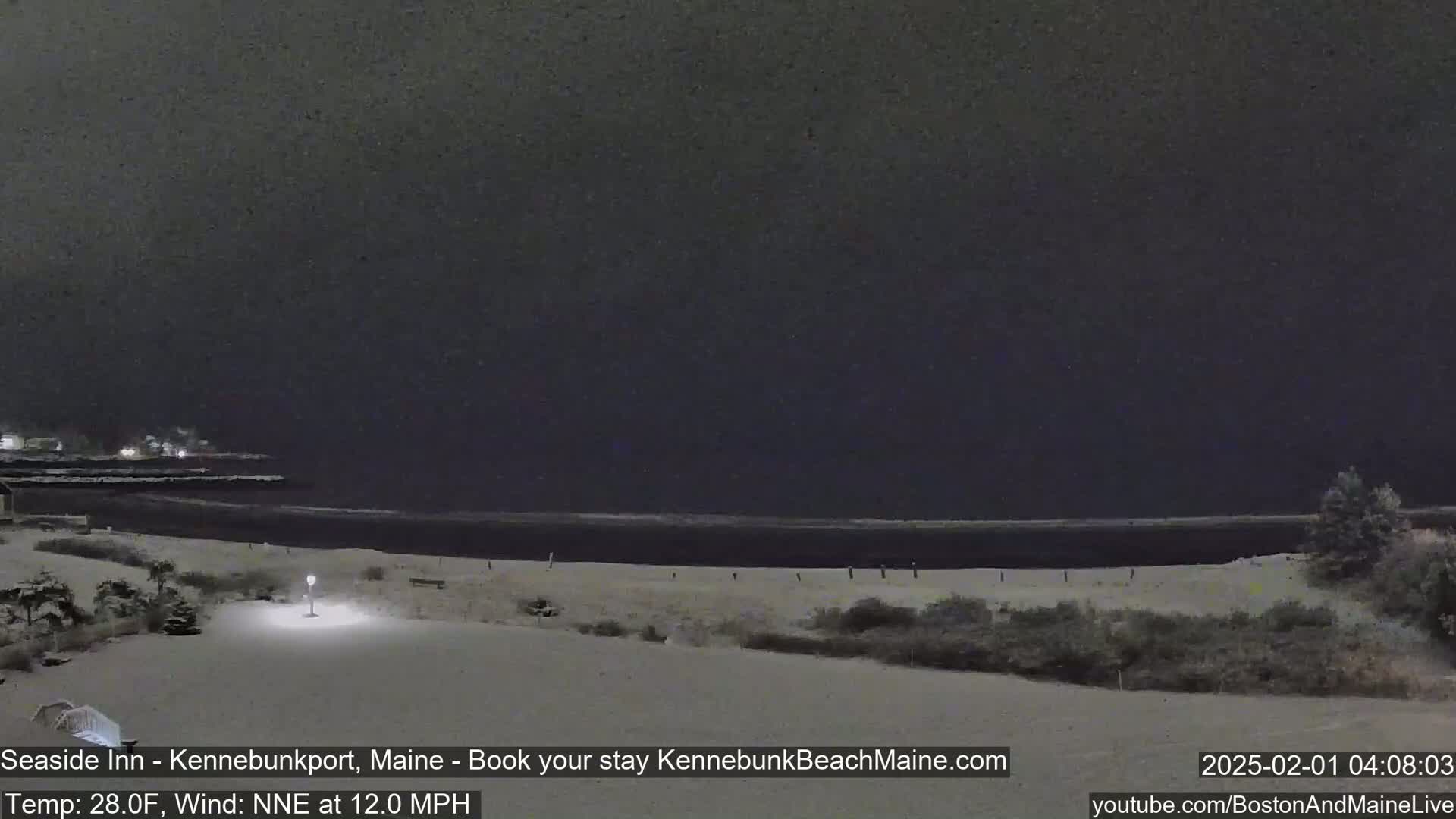 A snow-covered beach at night is seen under a dark, cloudy sky.