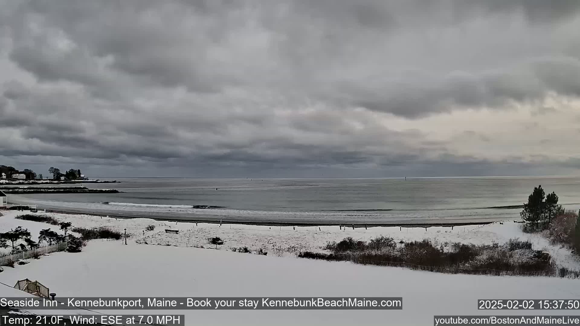 A snow-covered beach and coastline are visible under a cloudy sky.