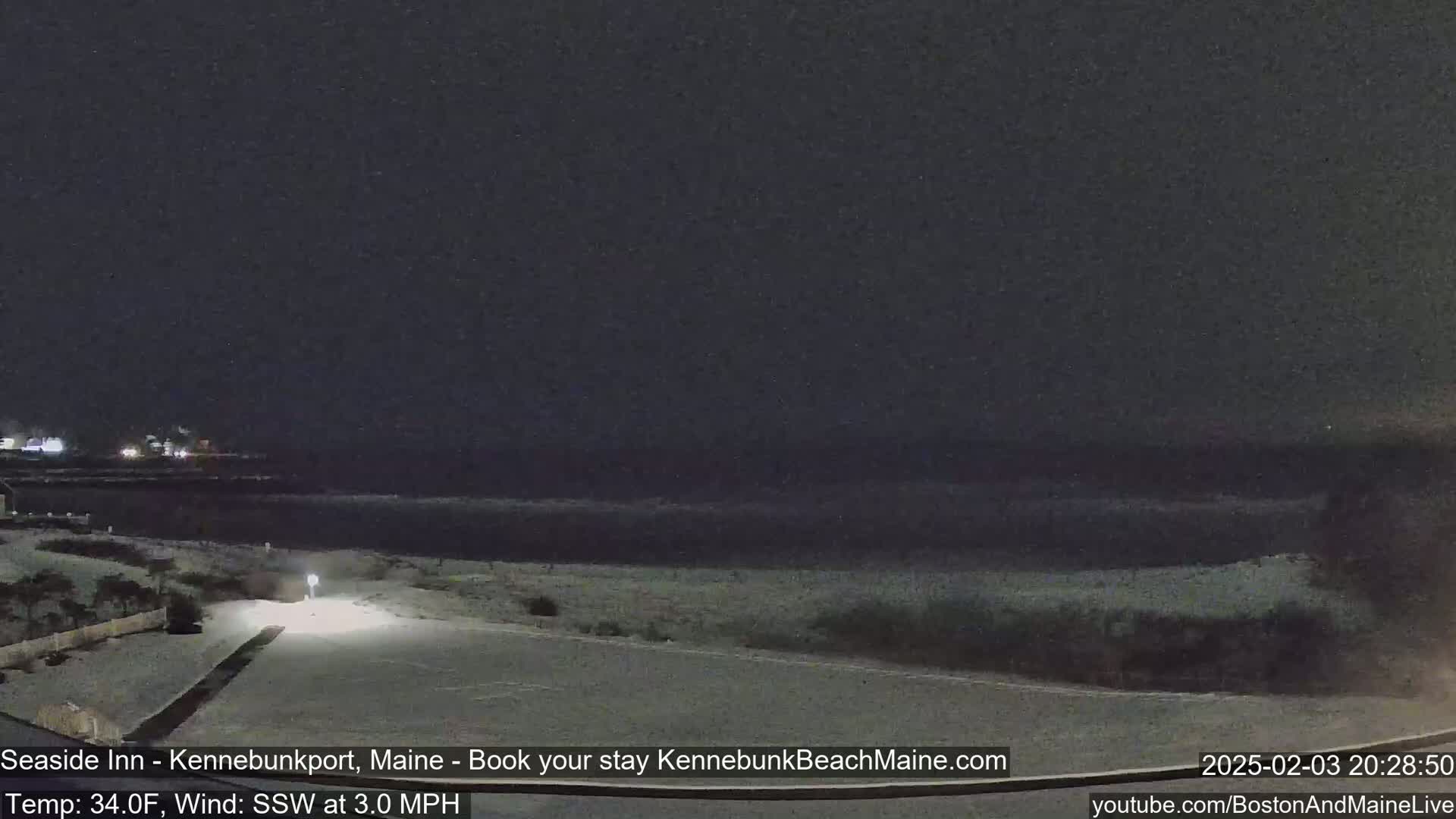 A snow-covered beach and roadway are visible at night under a dark sky.