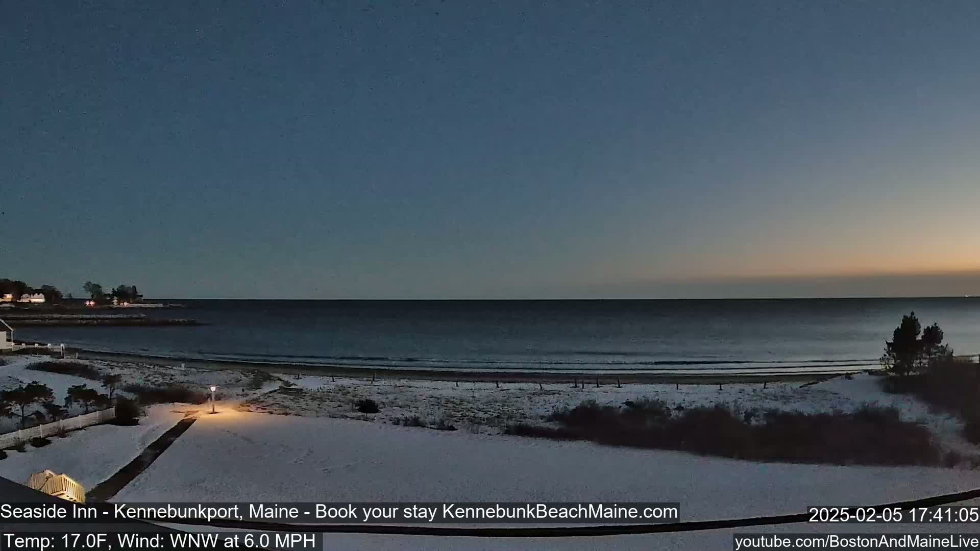 A snow-covered beach at twilight with a calm ocean and a partly cloudy sky, under a 17°F temperature with a 6.0 mph wind from the west-northwest.