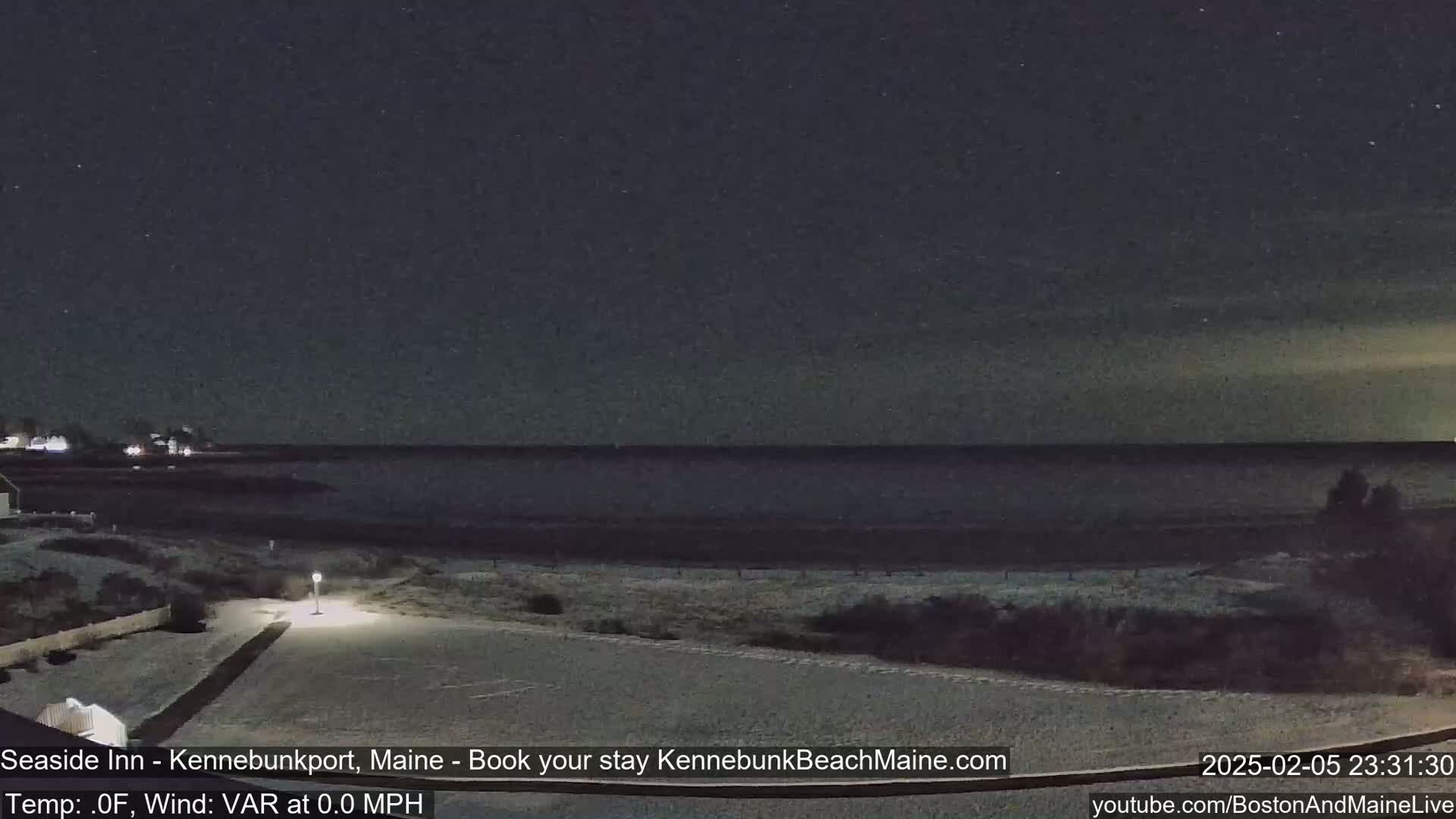 A snow-covered beach and parking lot are visible at night under a clear, starry sky.