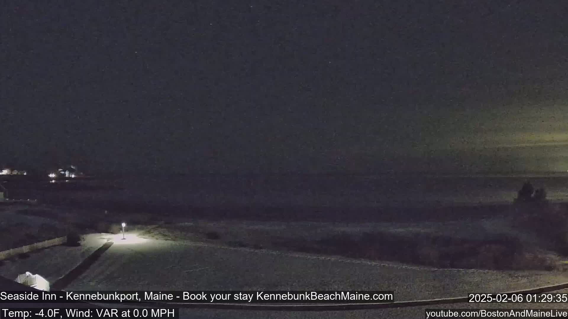 A nighttime view of a snow-covered beach and shoreline under a dark, clear sky.
