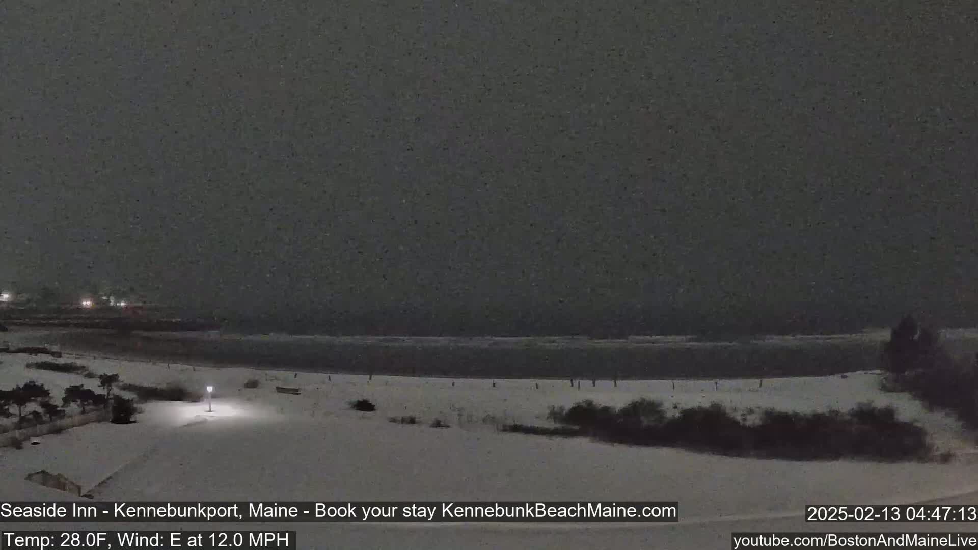 A snow-covered beach at night, with a dark, overcast sky and a calm ocean.