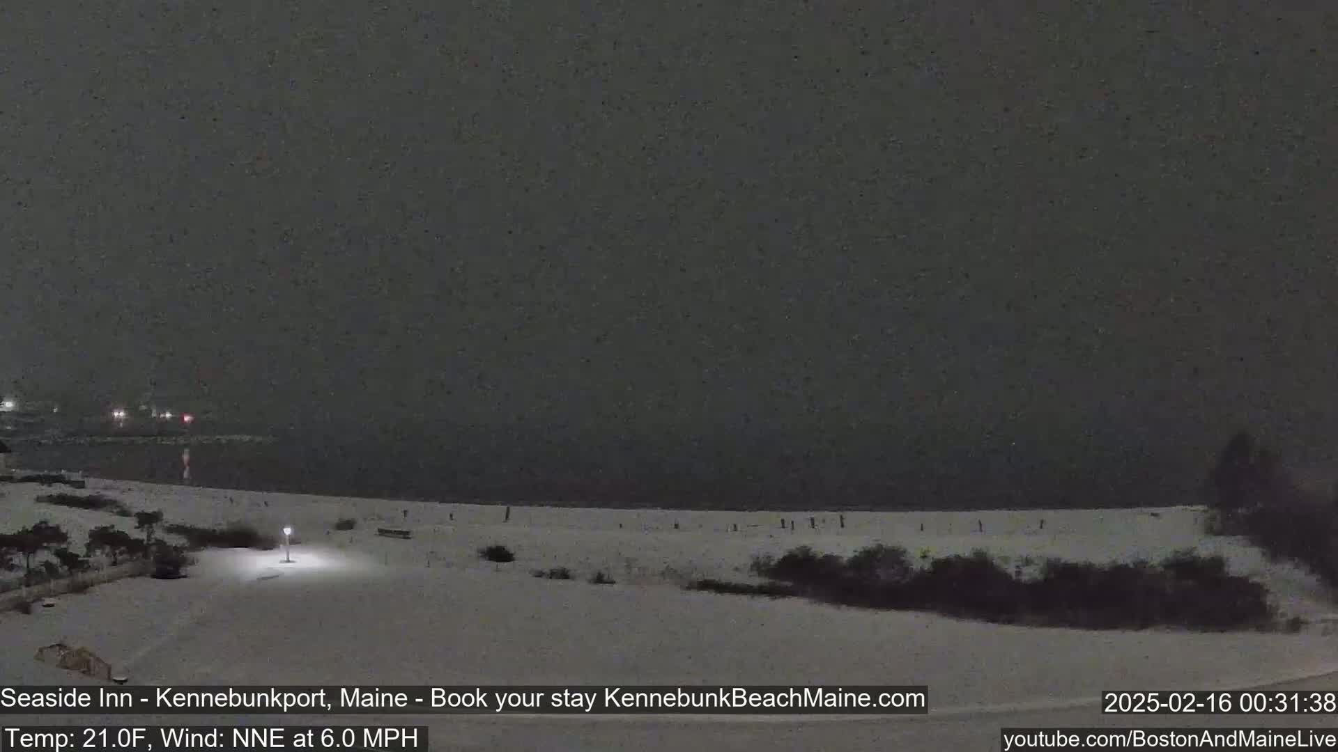 A snow-covered beach at night is seen under a dark, snowy sky.