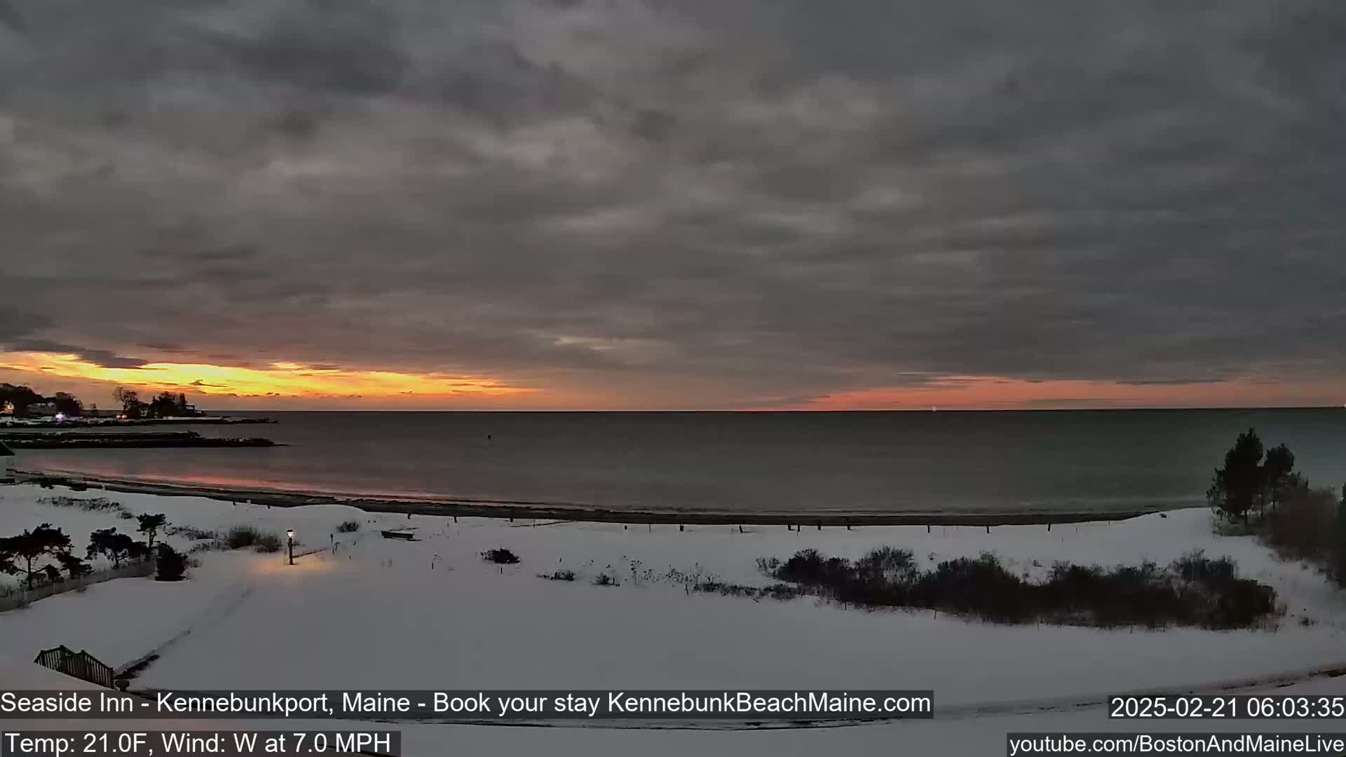 A snowy beach at sunrise under a mostly cloudy sky.