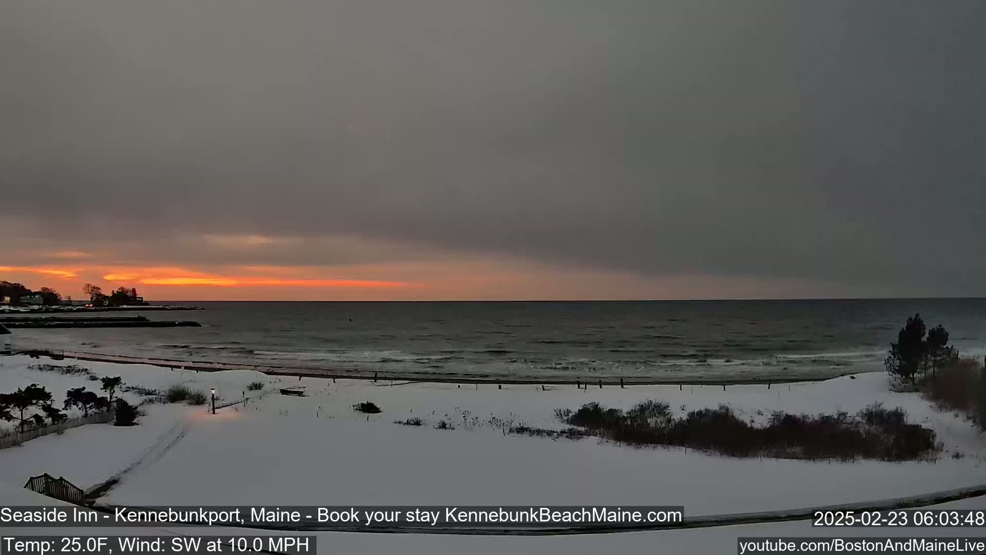A snow-covered beach at sunrise, with a dark gray sky and a southwest wind blowing at 10 mph.