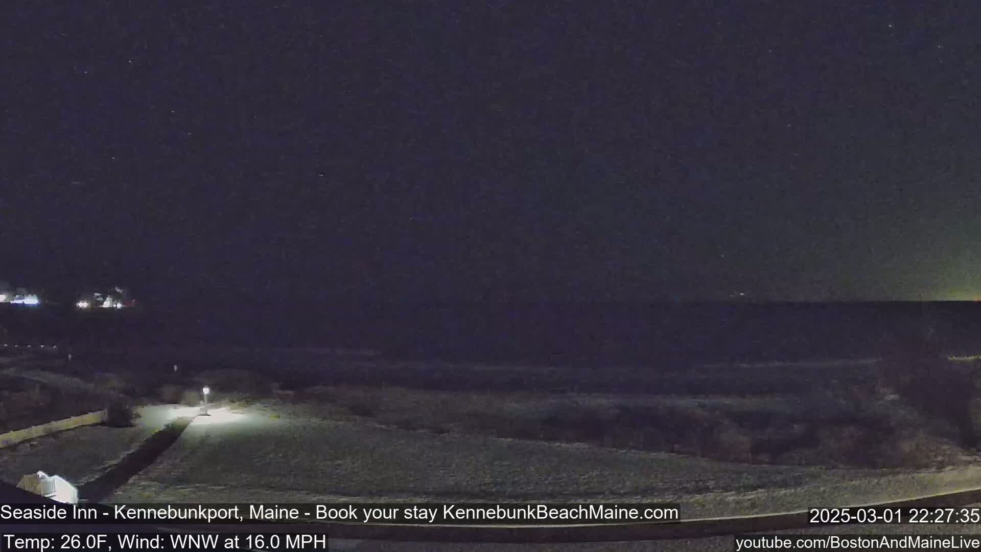 A snow-covered path leads to a dark, starlit ocean under a clear night sky with a 16 mph wind.