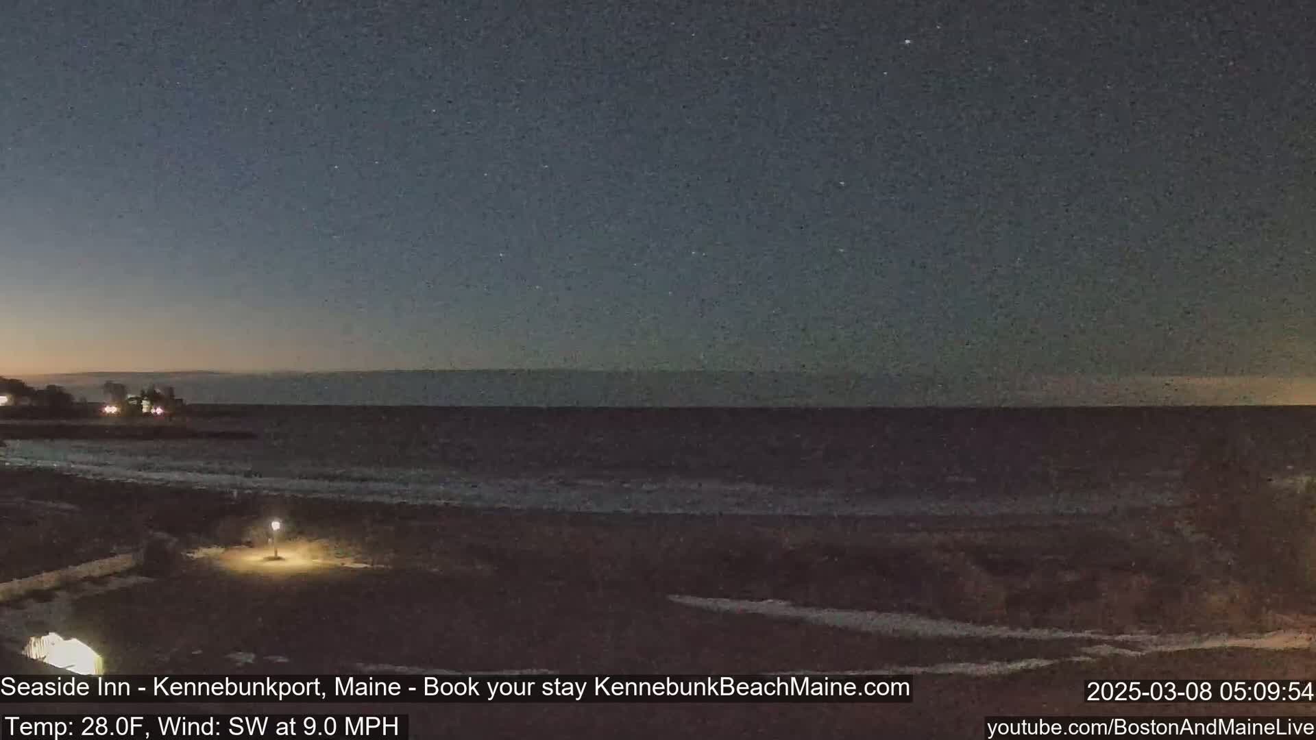 A dark, nighttime beach scene shows a calm ocean under a starry sky with a faint light on the shore.