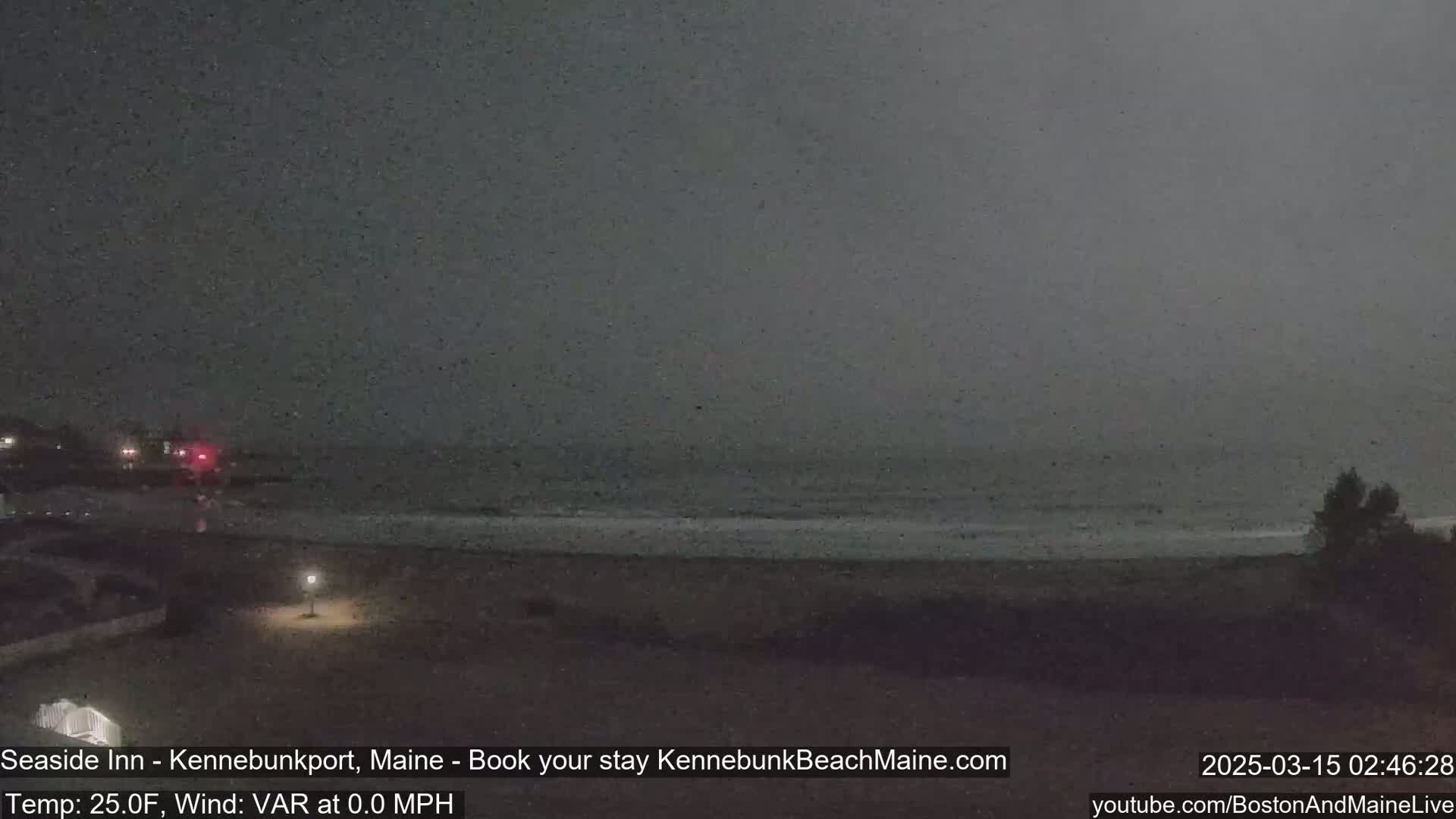 A dark, nighttime beach scene shows a calm ocean under a gray sky.