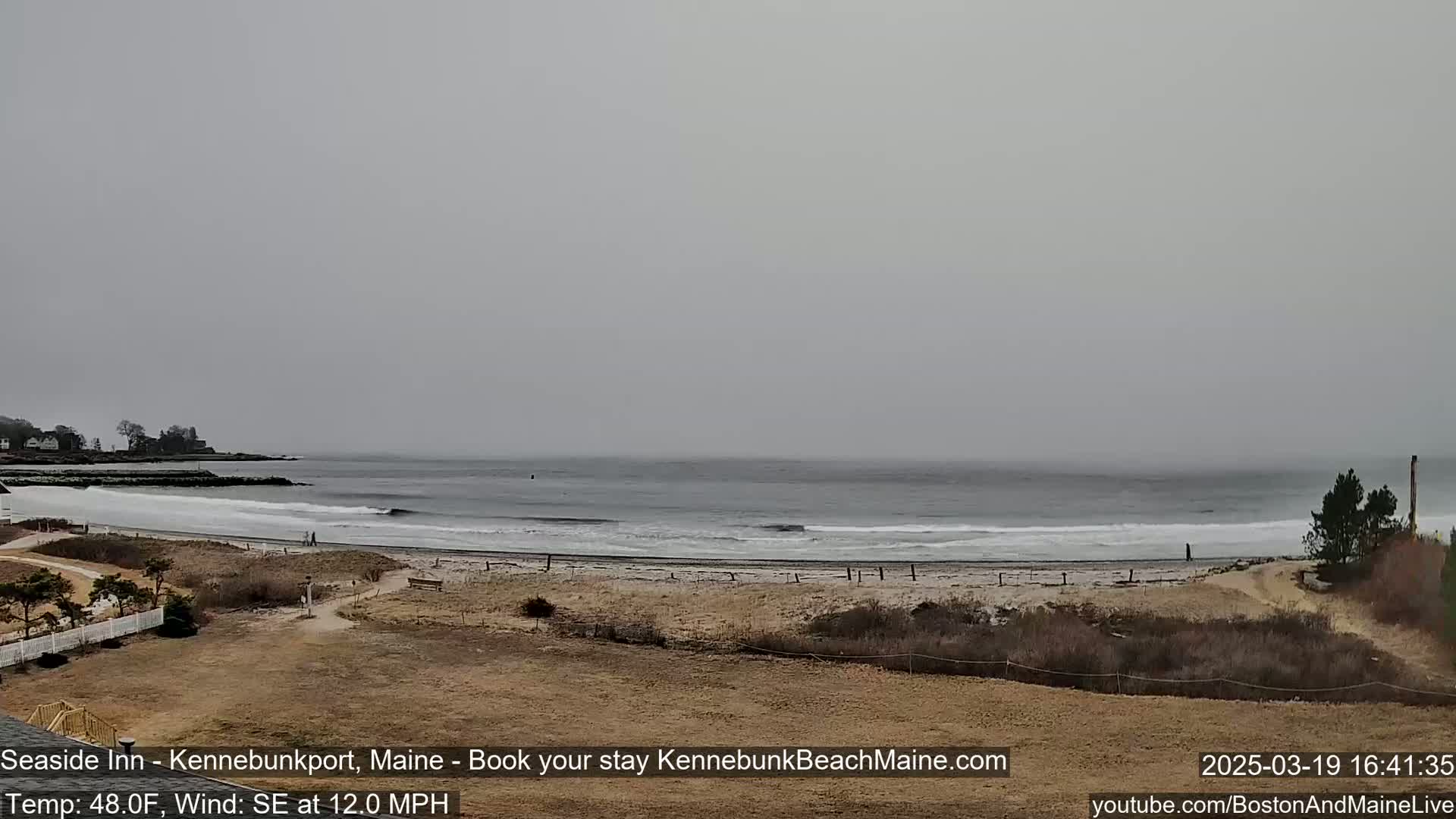 A view of a beach with a gray, overcast sky and moderate southeast wind shows small waves lapping the shore.