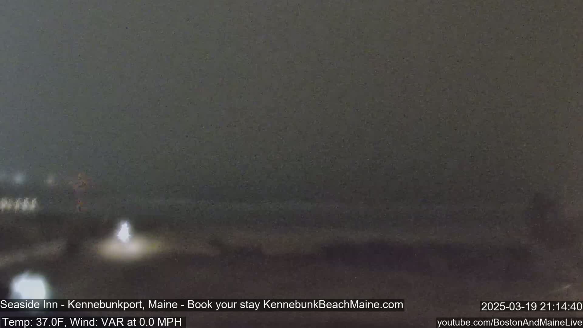 A dark, nighttime scene shows a blurry, indistinct coastal area under overcast skies.