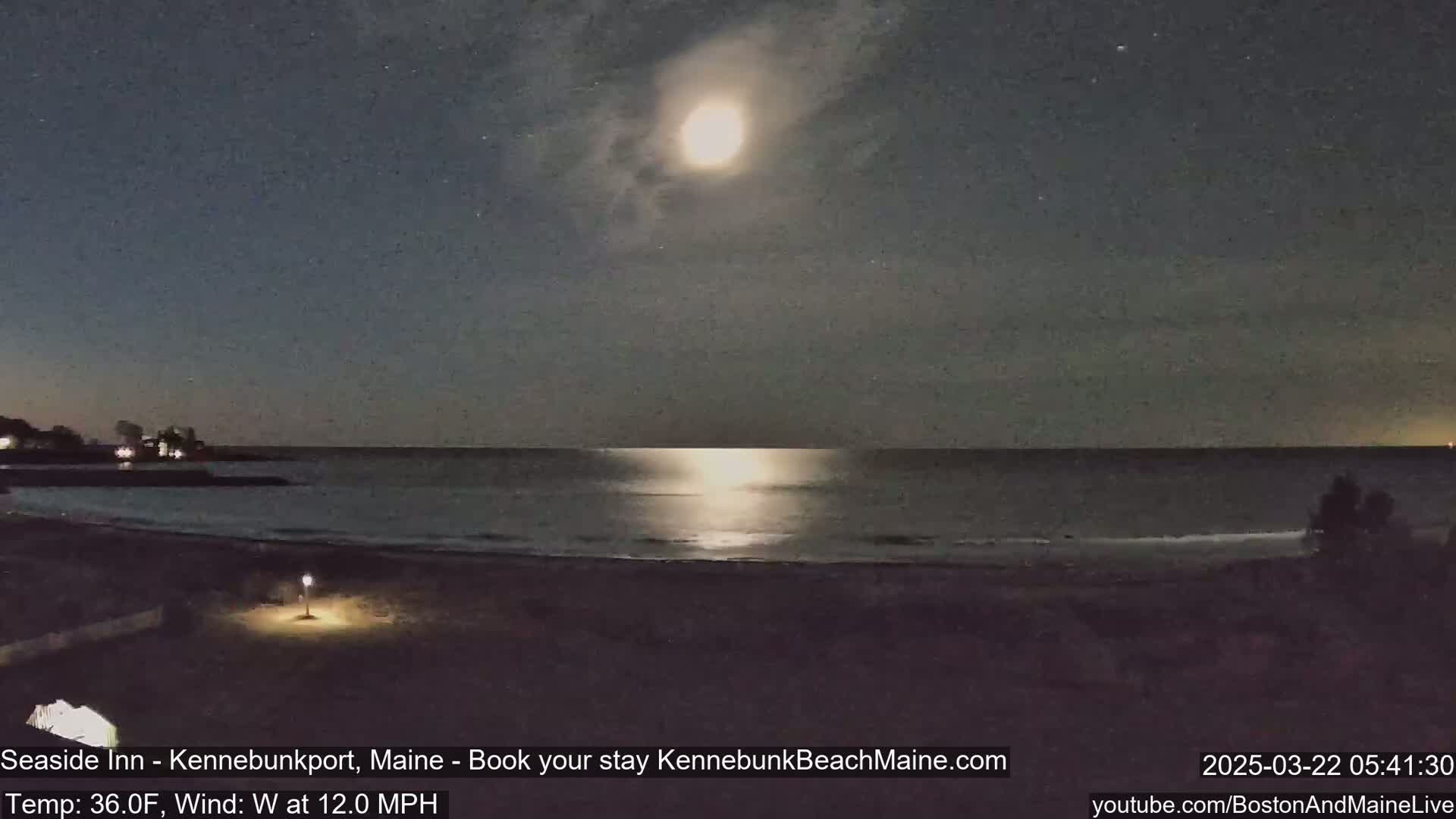 A bright moon illuminates a dark, wavy ocean at night with a 12 mph west wind and a temperature of 36°F.