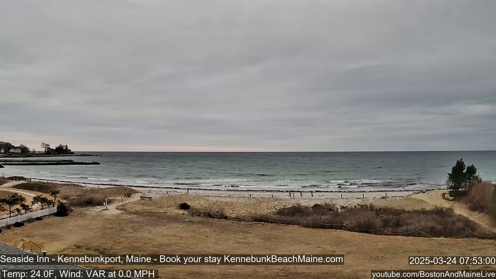 A sandy beach with calm waves and a mostly cloudy sky stretches to the horizon.