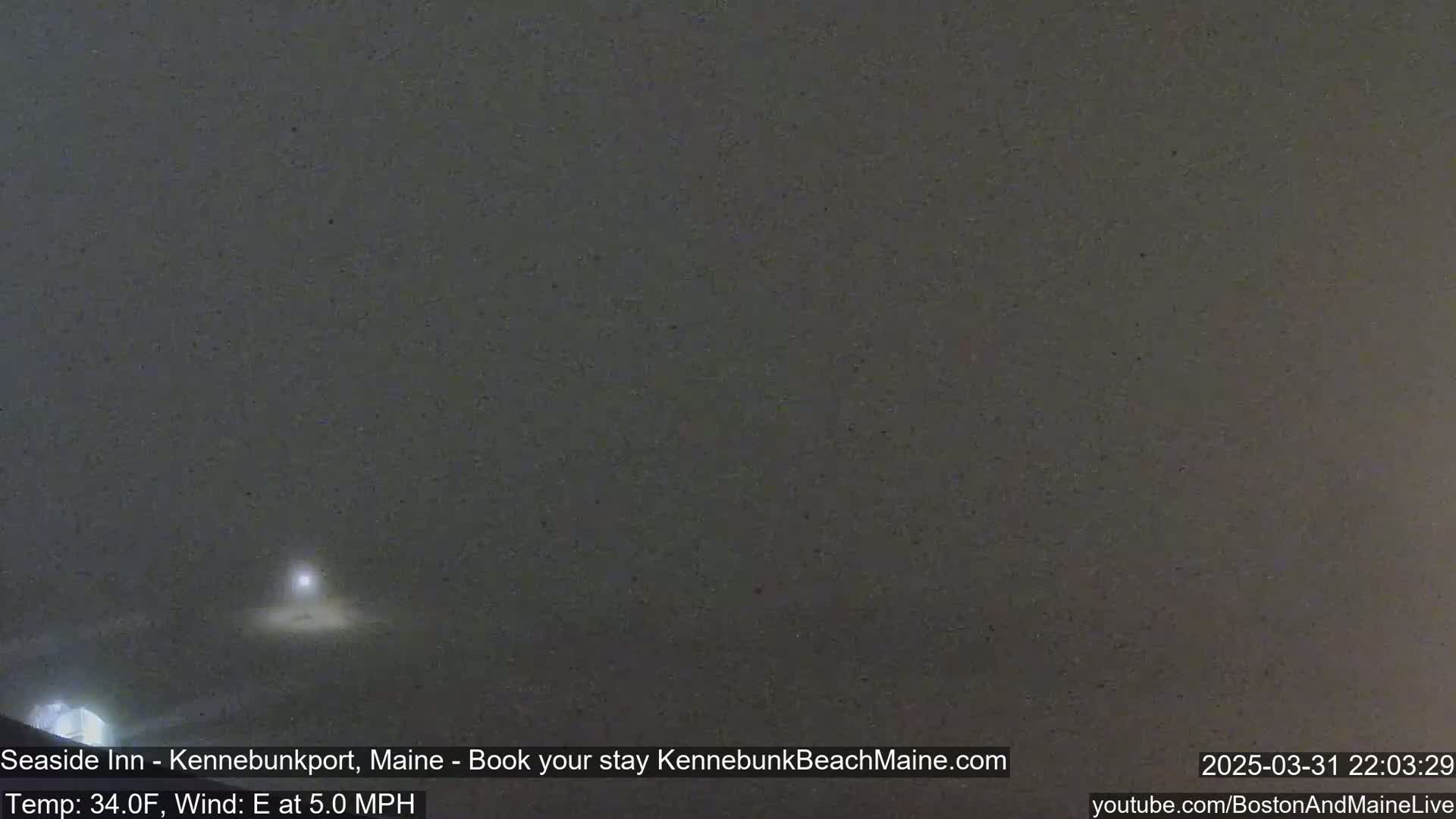 A nighttime, snowy scene is shown with a faint light source visible in the distance.