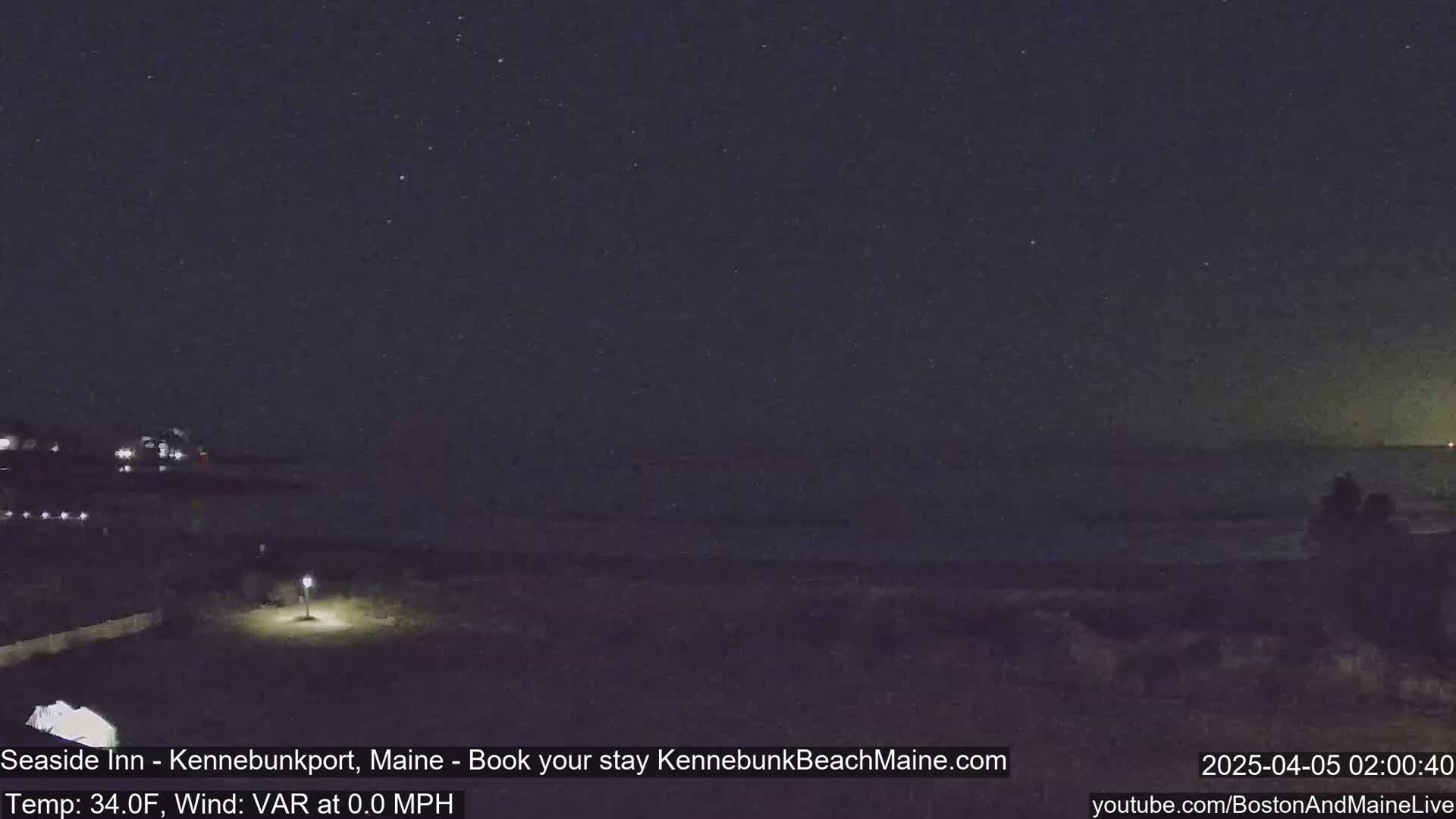 A nighttime view of a dark ocean shore under a starry sky.