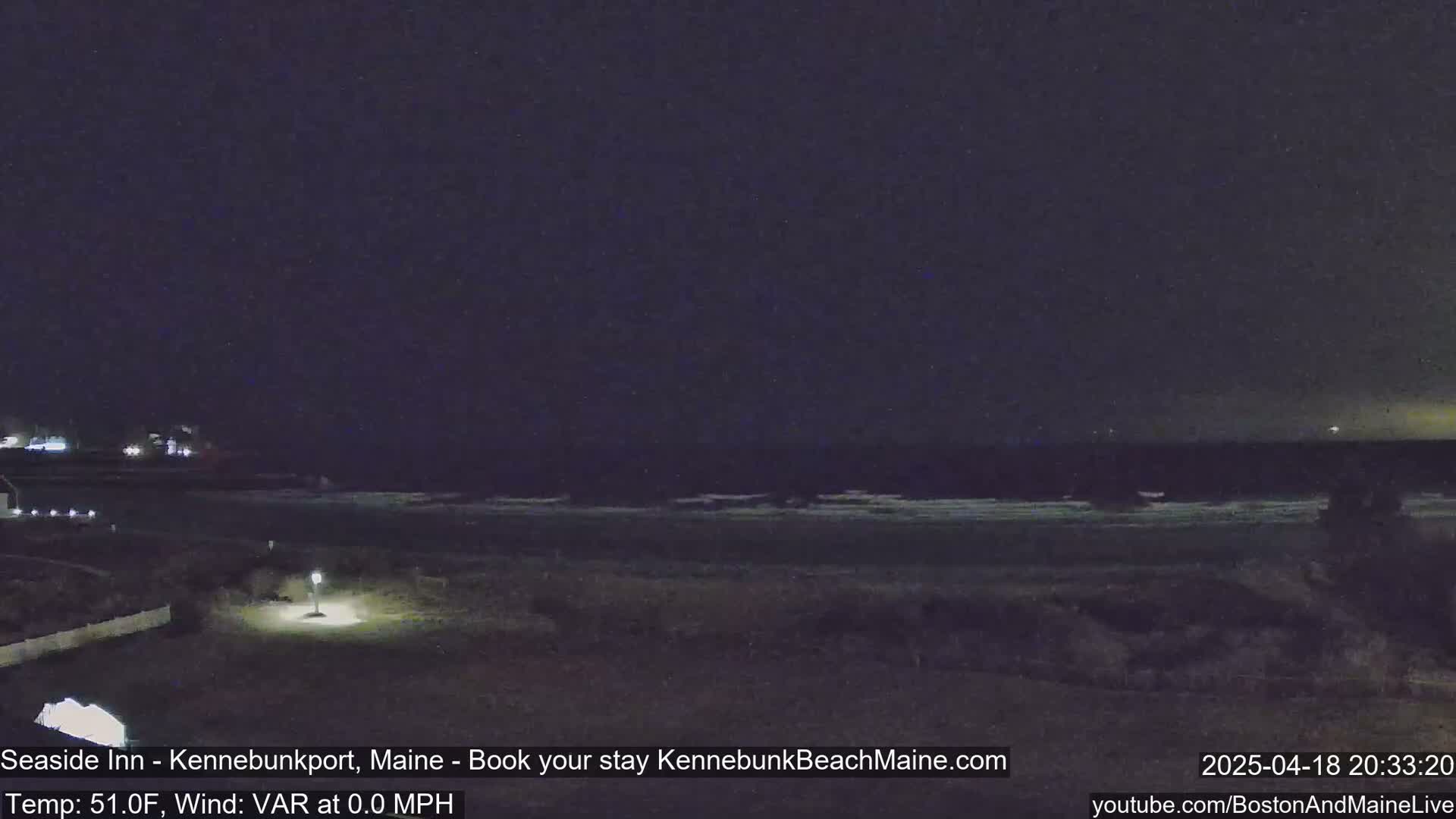 A nighttime view of a dark ocean with a calm, slightly visible surf under a clear, dark sky.