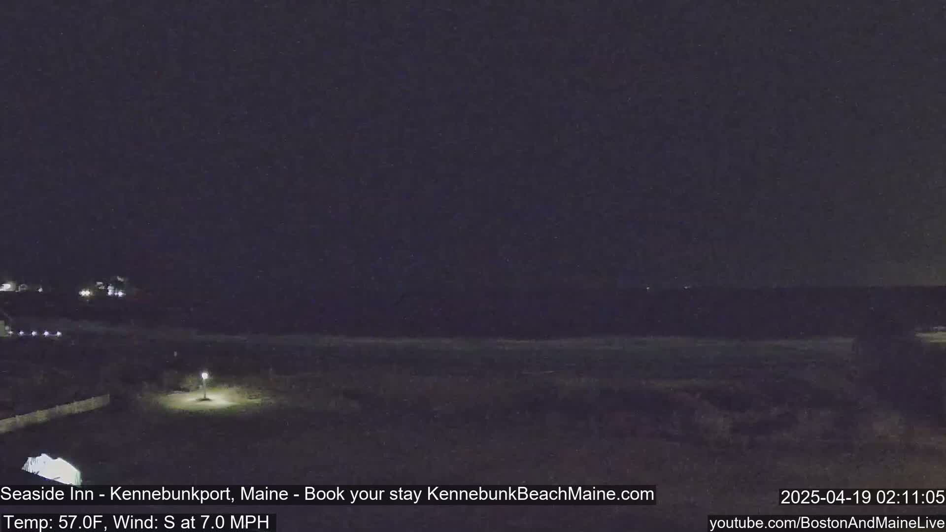 A nighttime view of a dark beach and ocean under a clear, dark sky.