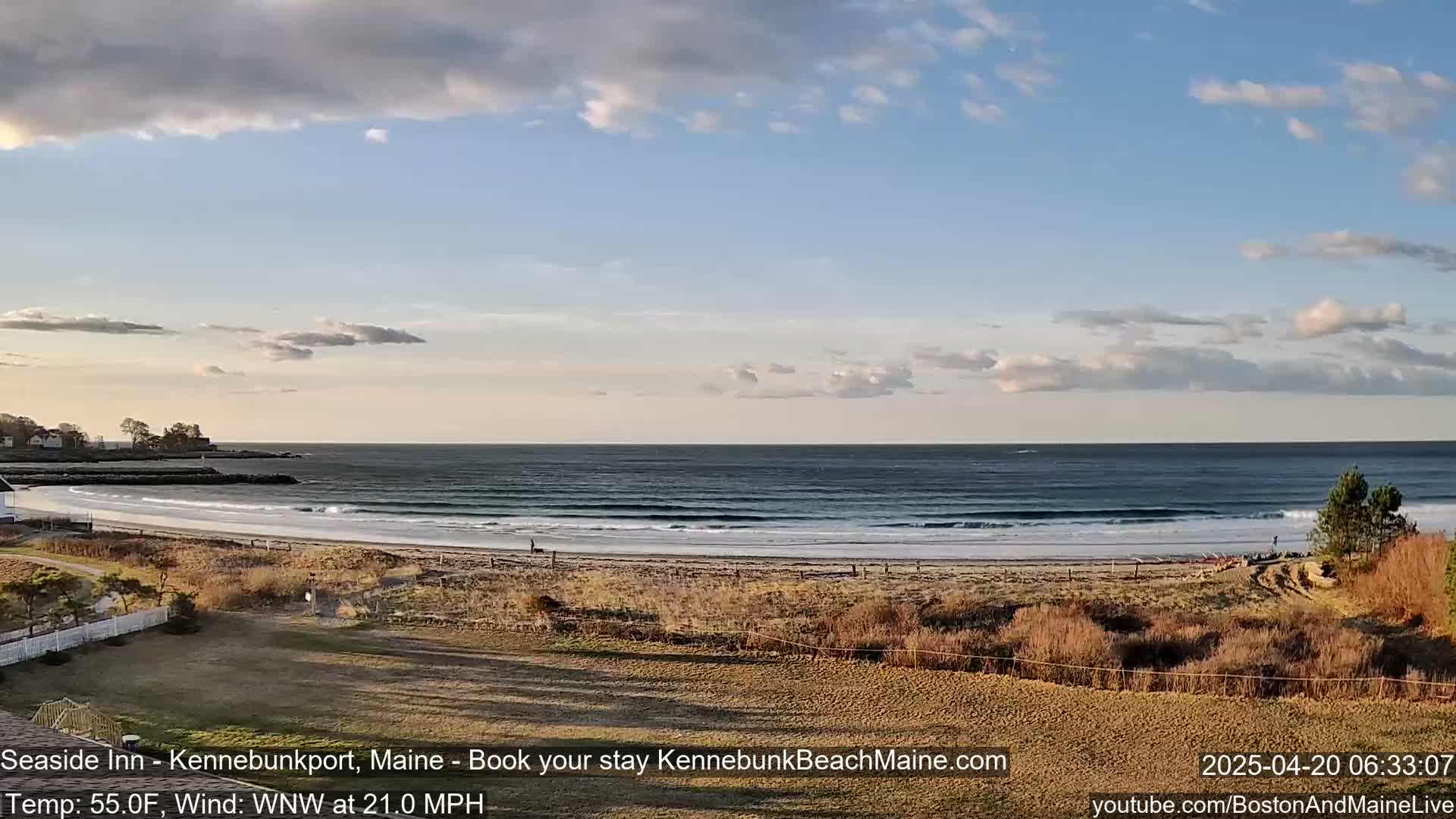 A sandy beach with gentle waves under a partly cloudy sky.