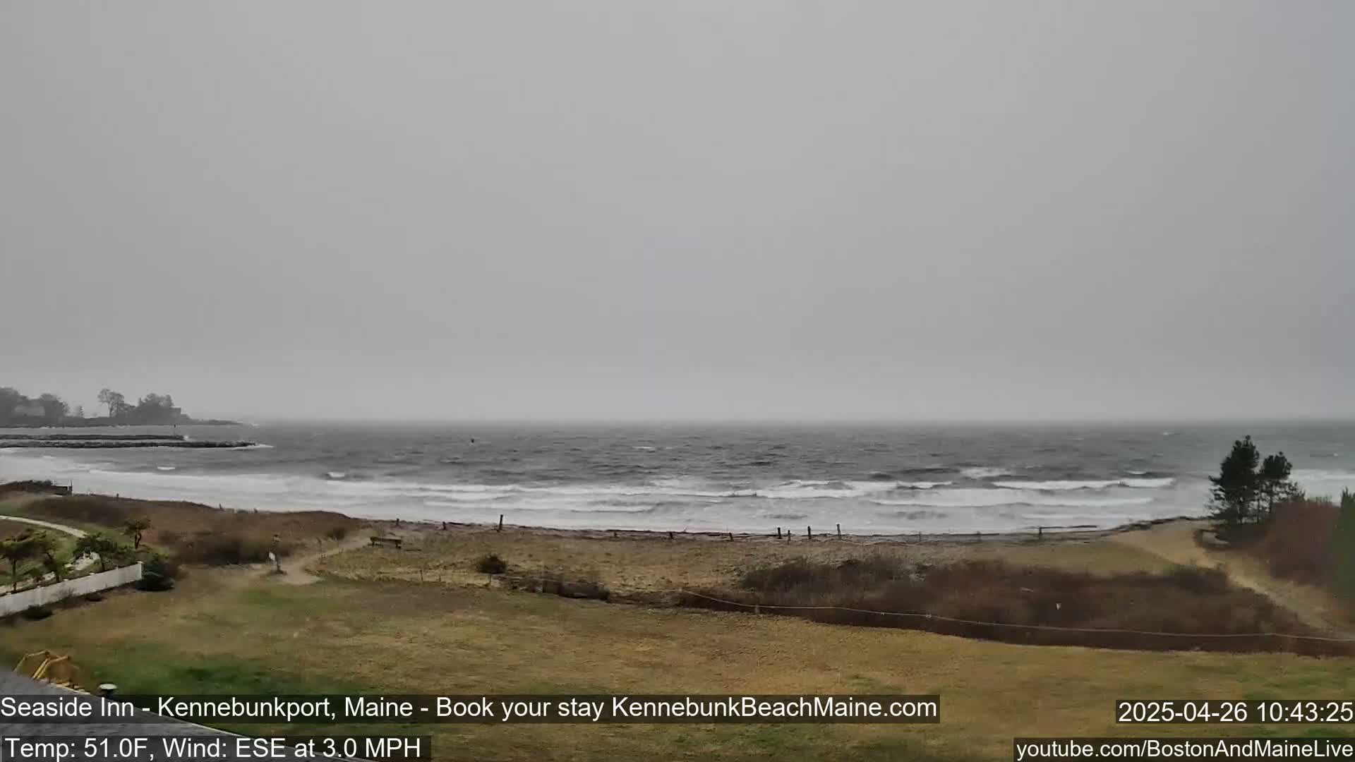 A view of a beach with a choppy ocean under an overcast sky.