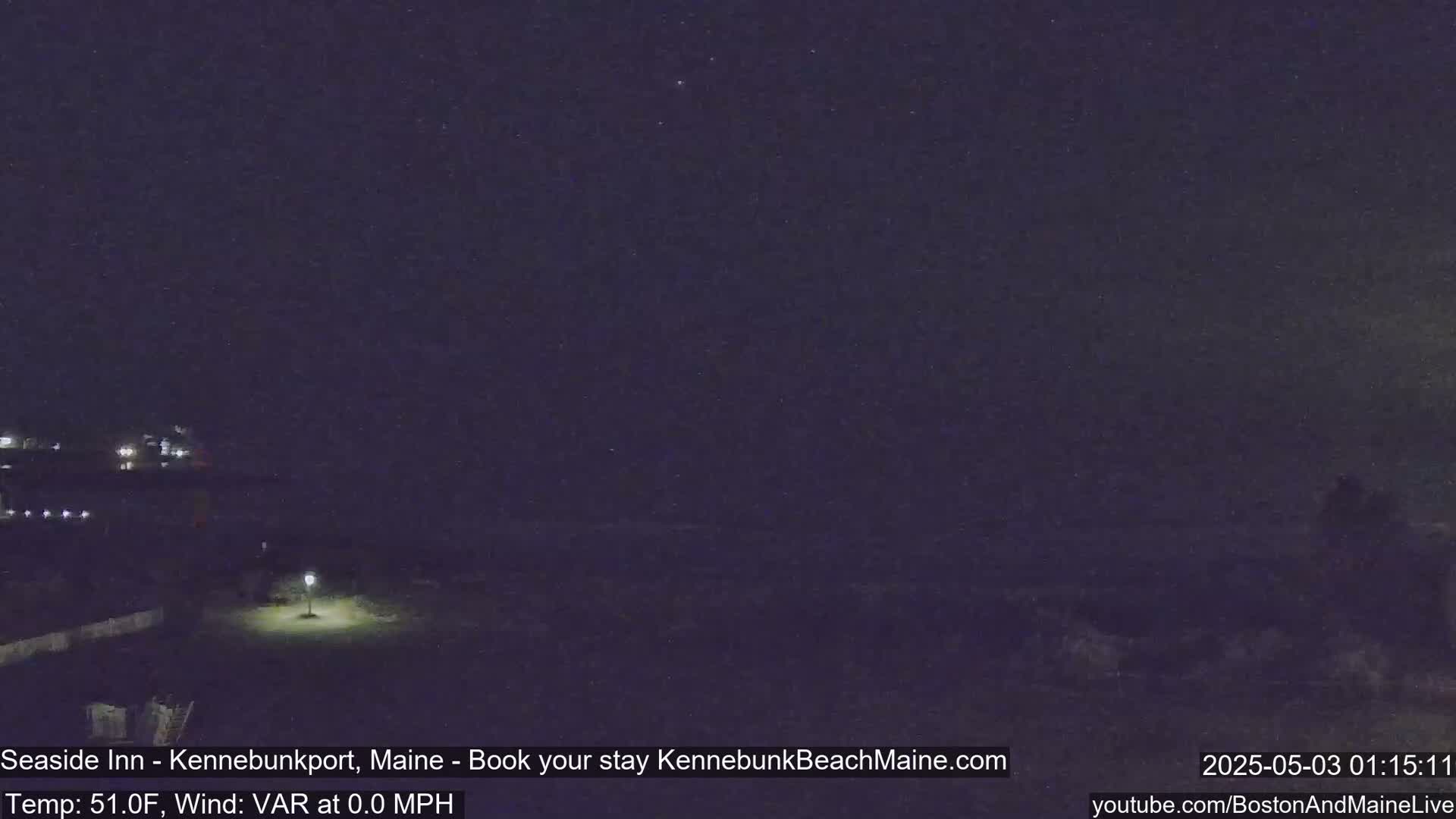 A dark nighttime scene shows a dimly lit coastal area with a calm sea under a mostly clear, starlit sky.