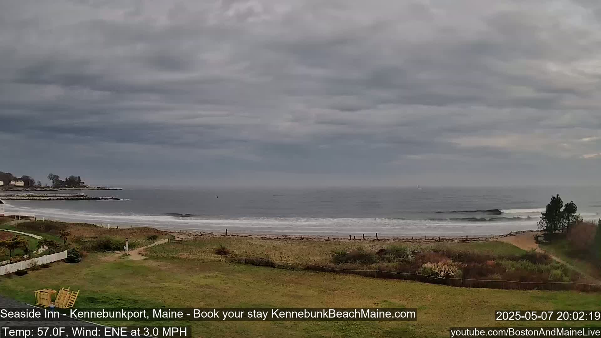 A wide shot of a sandy beach with gentle waves under an overcast sky.