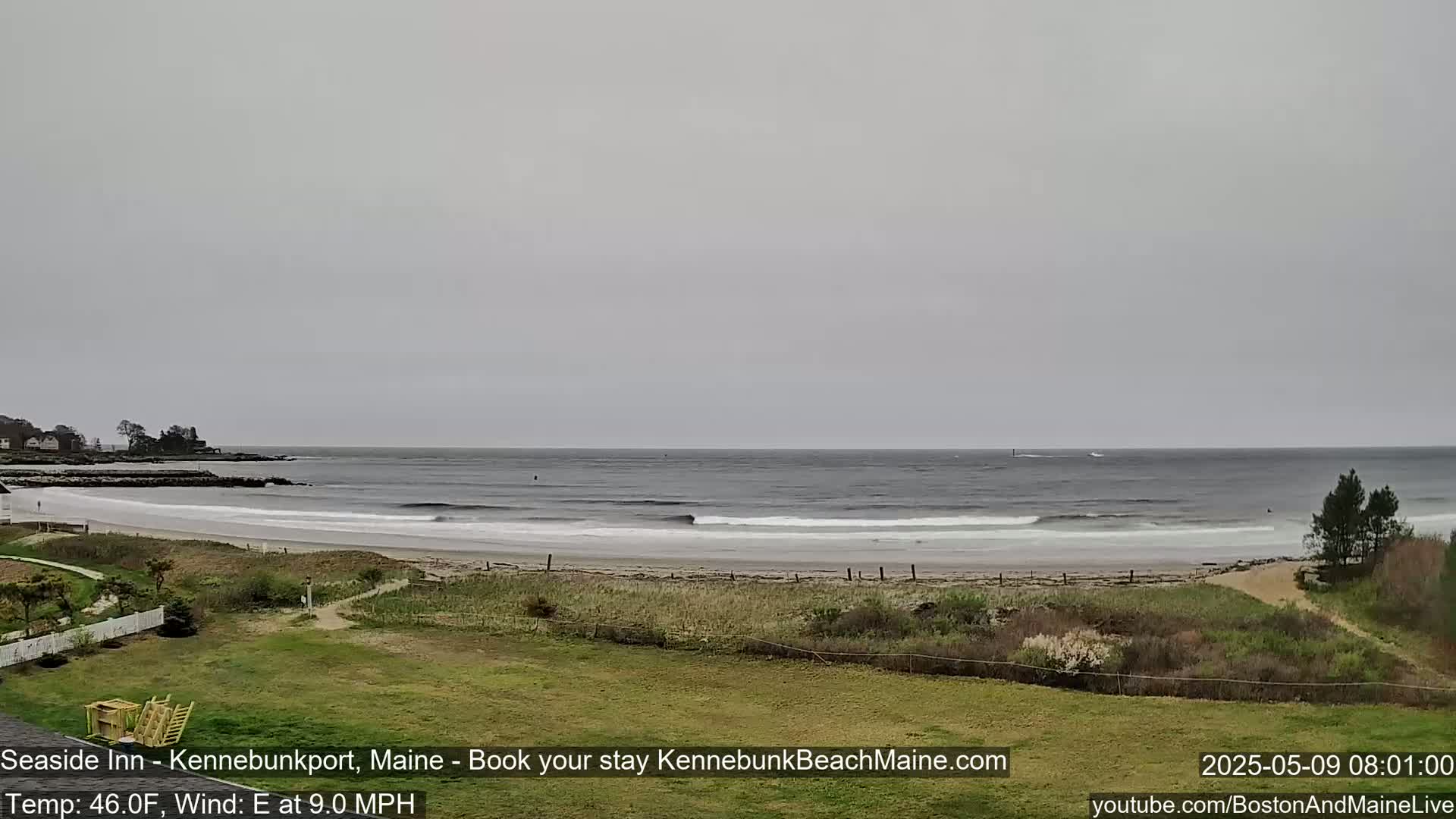 A wide, sandy beach with gentle waves laps the shore under an overcast sky.