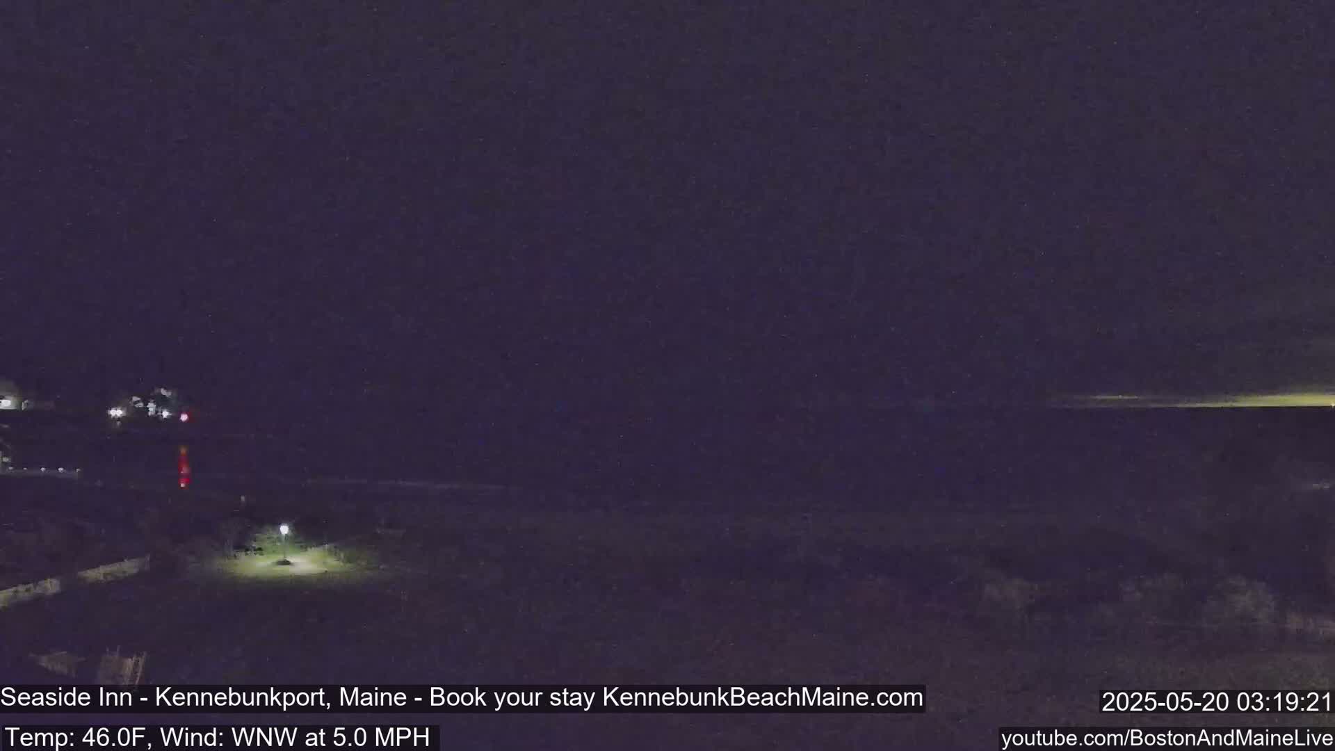 A nighttime coastal scene shows a dark beach and ocean under a mostly clear, dark sky with a faint light horizon.