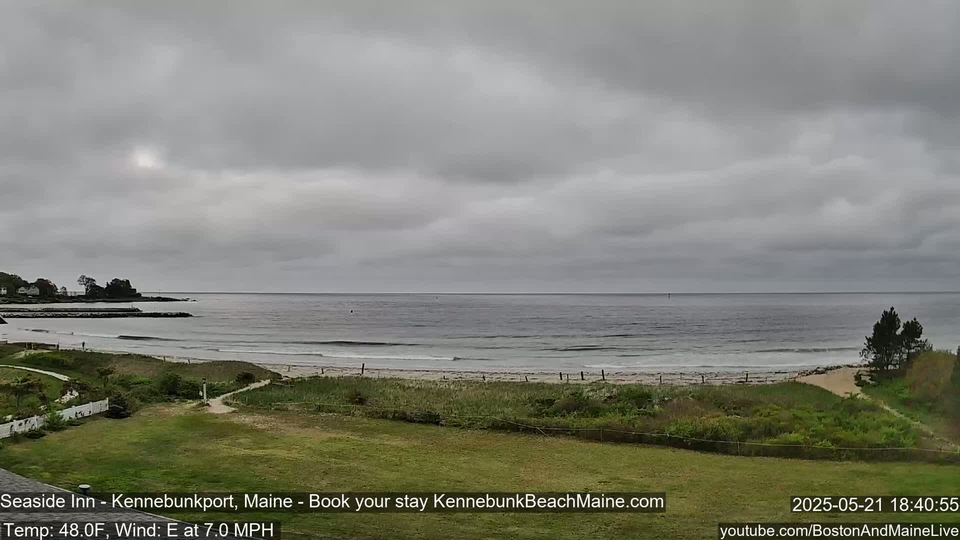 A view of a beach with gentle waves under an overcast sky.
