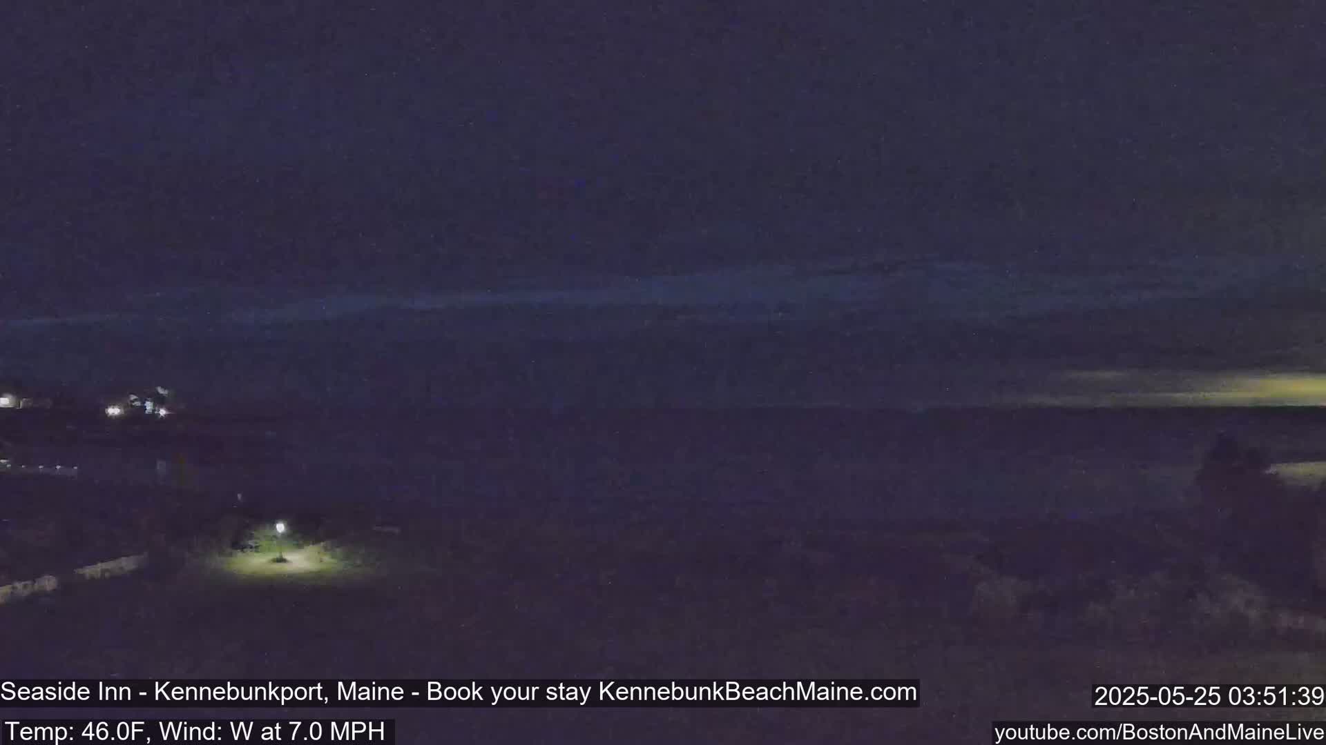 A nighttime coastal scene shows a dark ocean under a mostly clear, dark sky with a slight hint of light on the horizon.