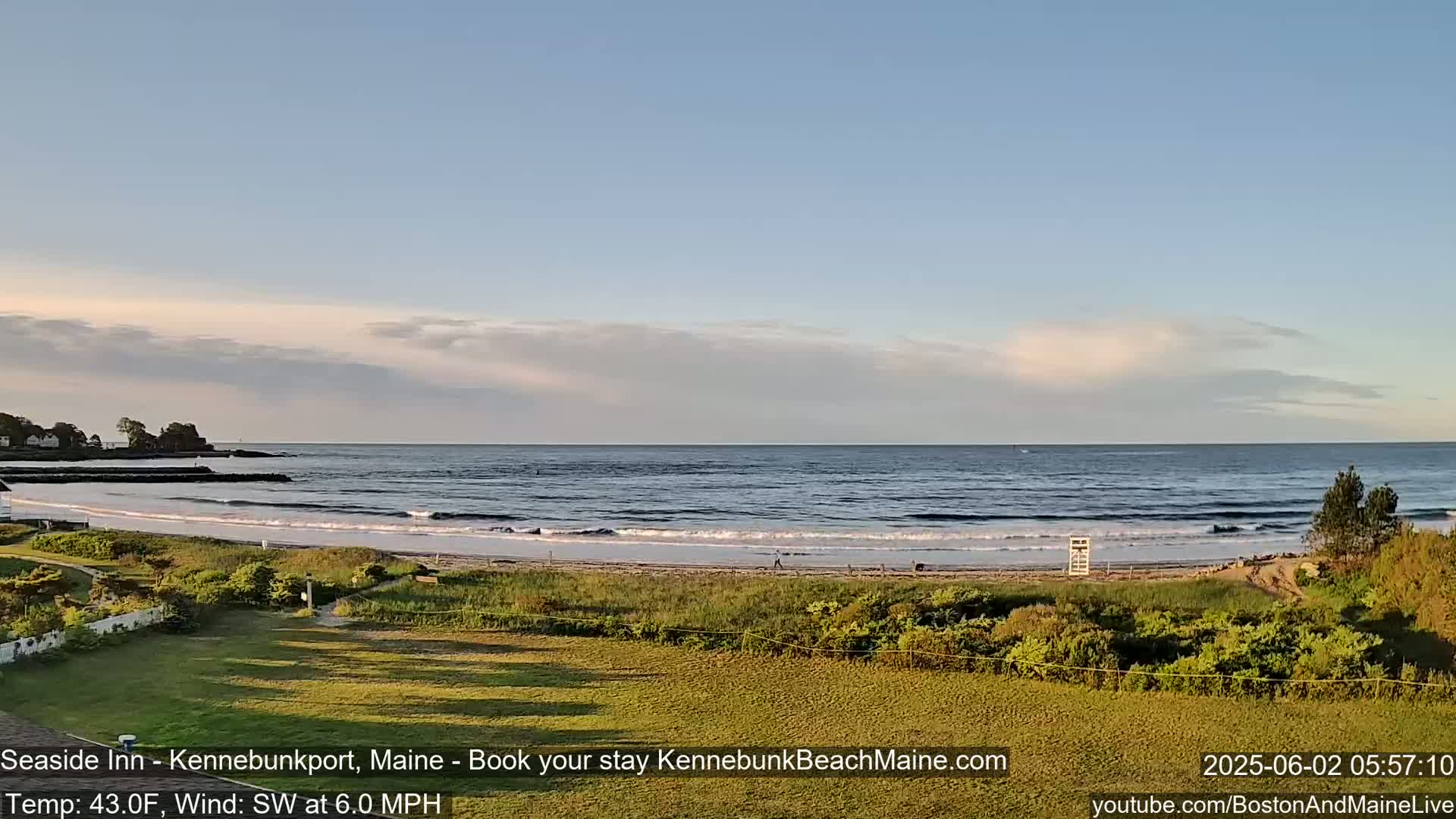 A sandy beach with gentle waves under a partly cloudy sky overlooks a calm ocean.