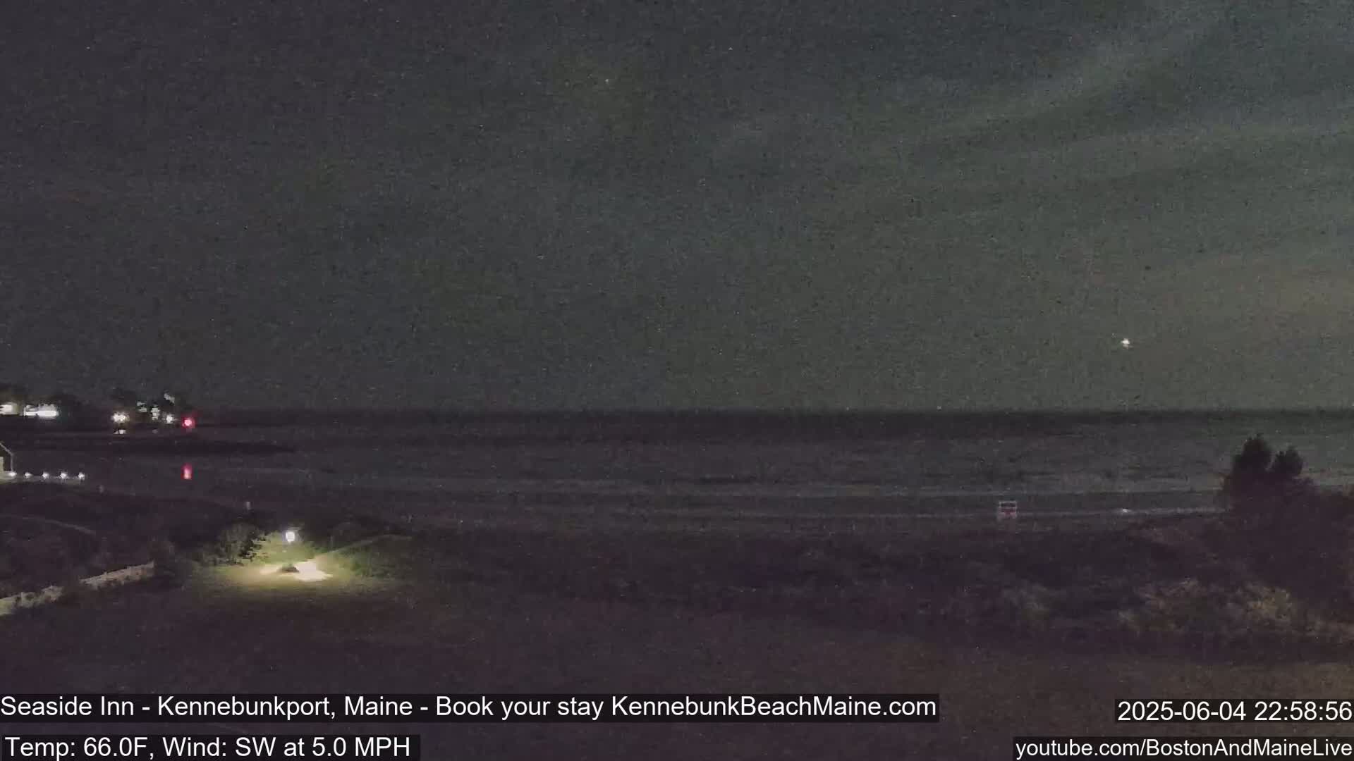 A dark, nighttime beach scene with calm water under a mostly clear sky and a light southwest wind.
