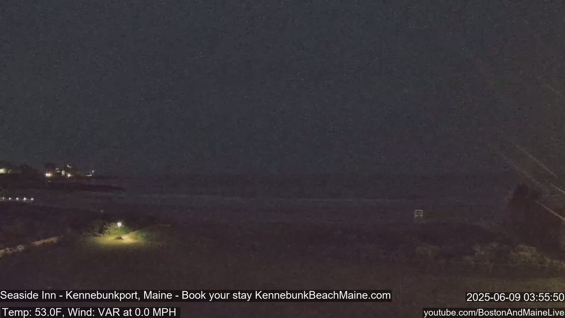 A nighttime view of a dark ocean and shoreline, under a clear, dark sky.