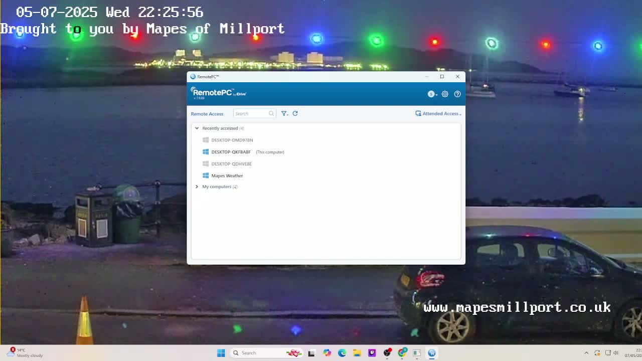 A nighttime view of a mostly cloudy waterfront scene with a computer screen showing a remote access program, and a car parked nearby.