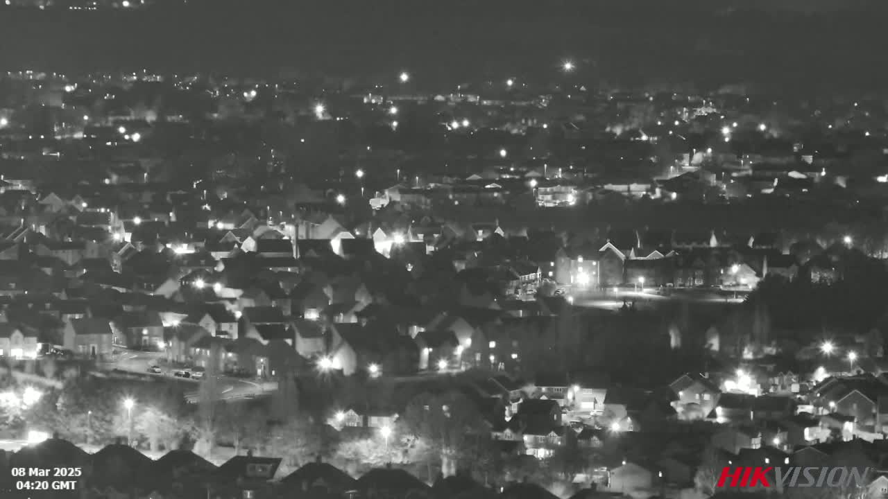 A nighttime, aerial view of a residential area with numerous houses illuminated by streetlights and individual home lights.
