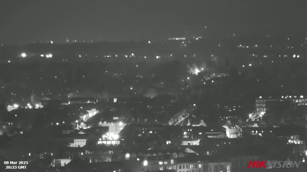 A nighttime, low-light aerial view of a city with many scattered lights.