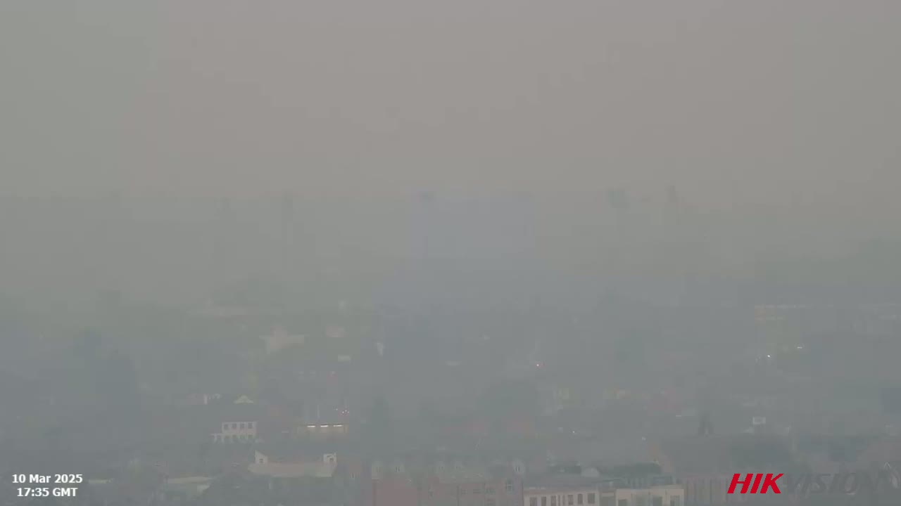 A hazy, smoky view of a town or city is visible from an elevated vantage point.