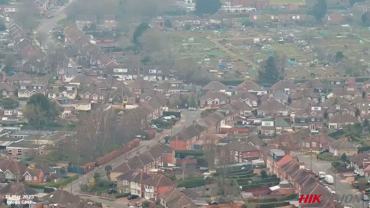 An aerial view shows a residential area with many houses and roads on an overcast day.