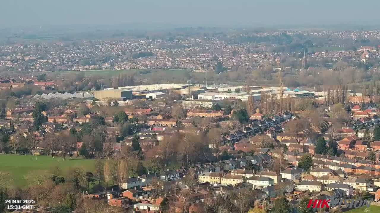 A sprawling suburban area with industrial buildings and a large green space is visible on a clear, sunny day.