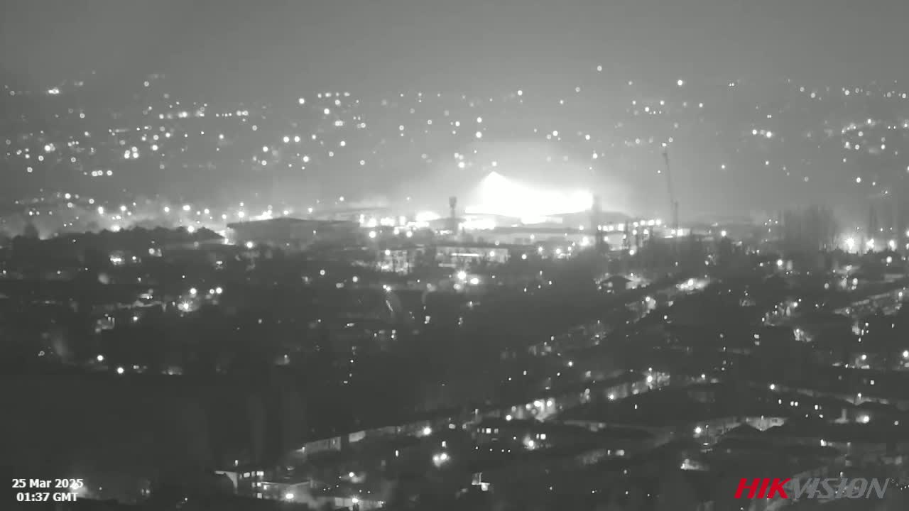 A nighttime, hazy view of a city with a large, bright light source in the distance.