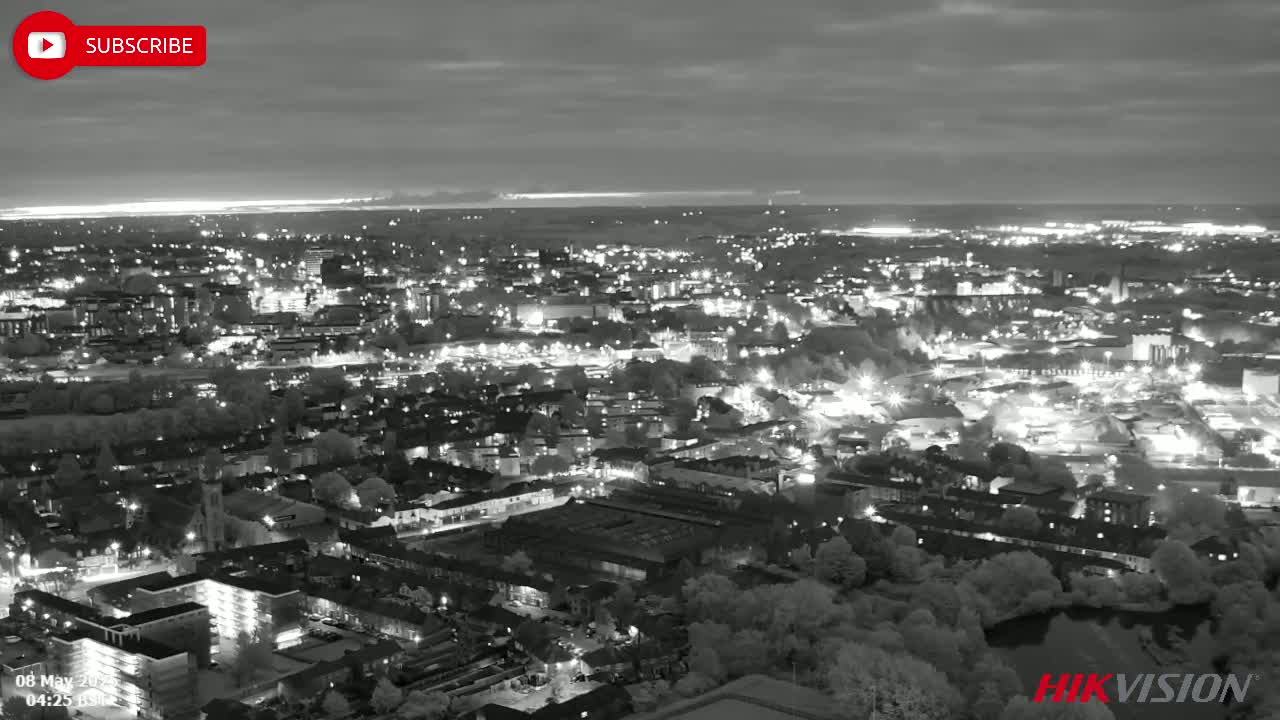 A nighttime aerial view of a city illuminated by streetlights under a cloudy sky.
