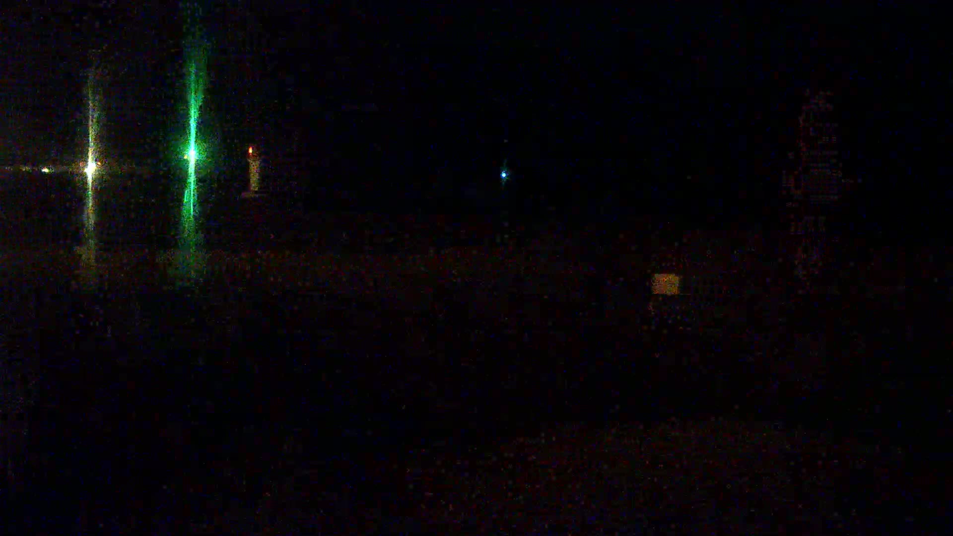 At night, several faint lights are visible in the dark, possibly from distant structures or vehicles.
