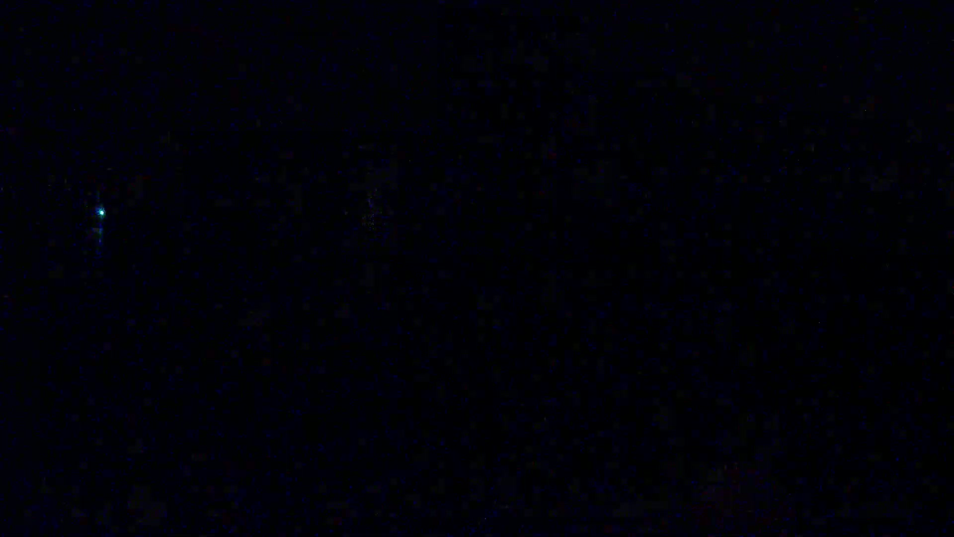 A dark, nighttime scene shows a small, bright light in the distance.