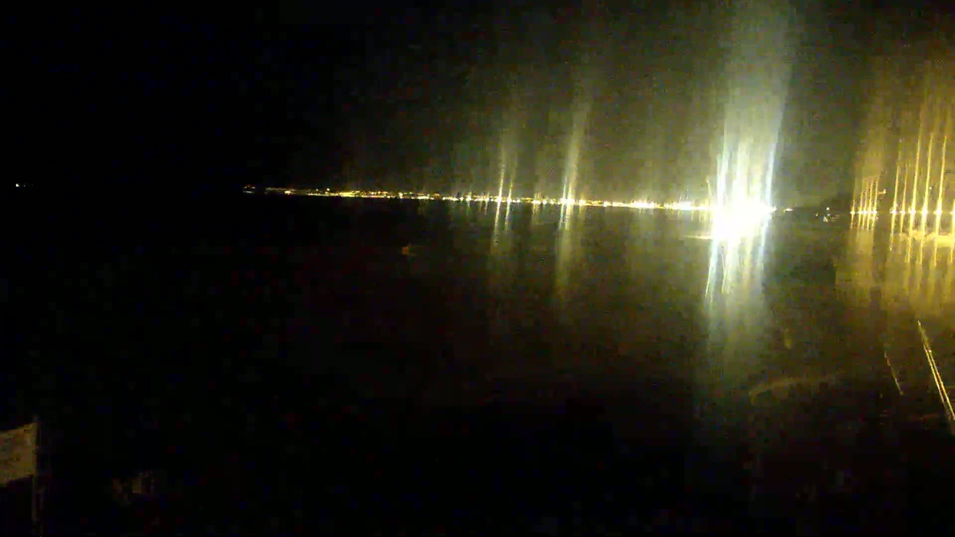 A dark body of water reflects the lights of a distant city at night.