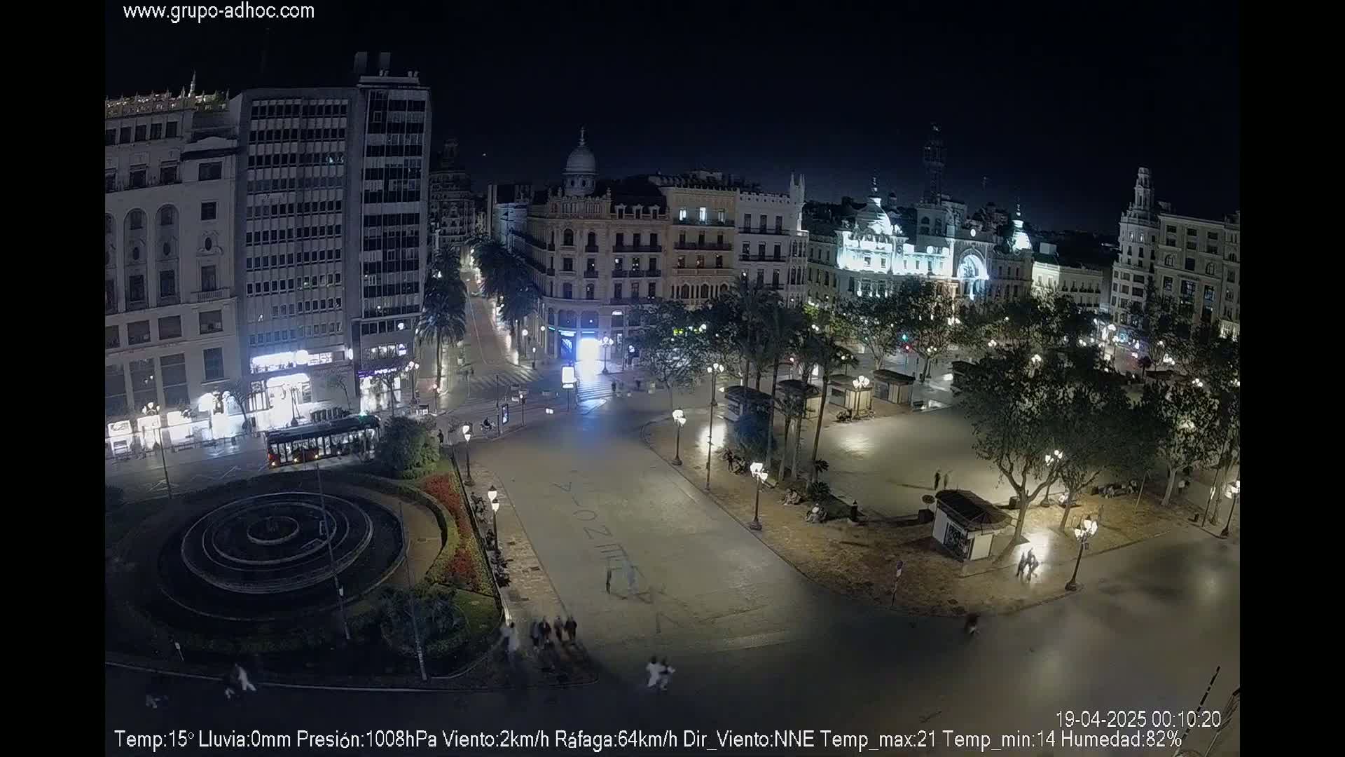 A nighttime view of a city square with buildings surrounding it, illuminated by streetlights, under a clear sky.