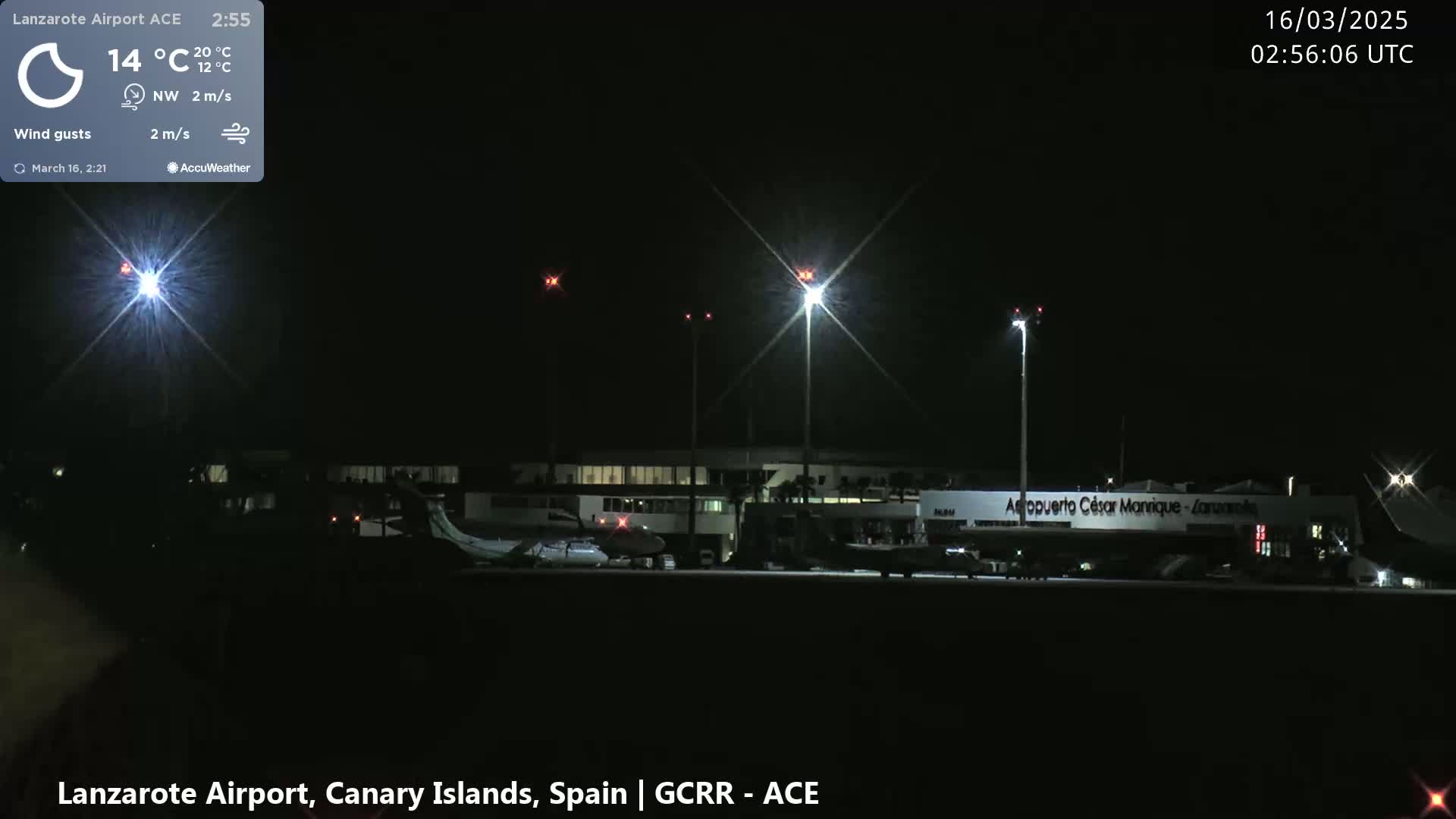A nighttime view of an airport with several planes parked on the tarmac under bright lights, with a calm, clear sky.
