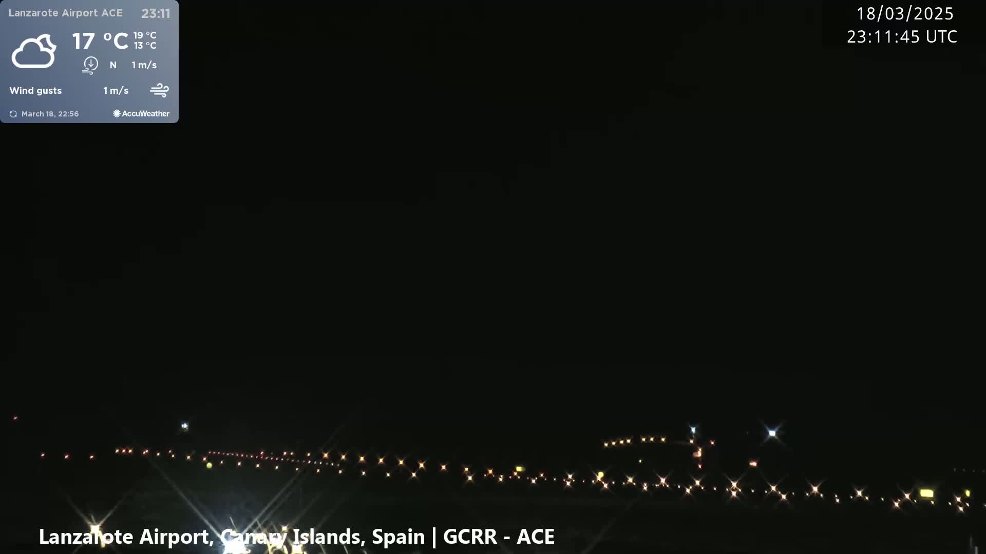 A nighttime view of an airport runway illuminated by lights under a clear, dark sky.
