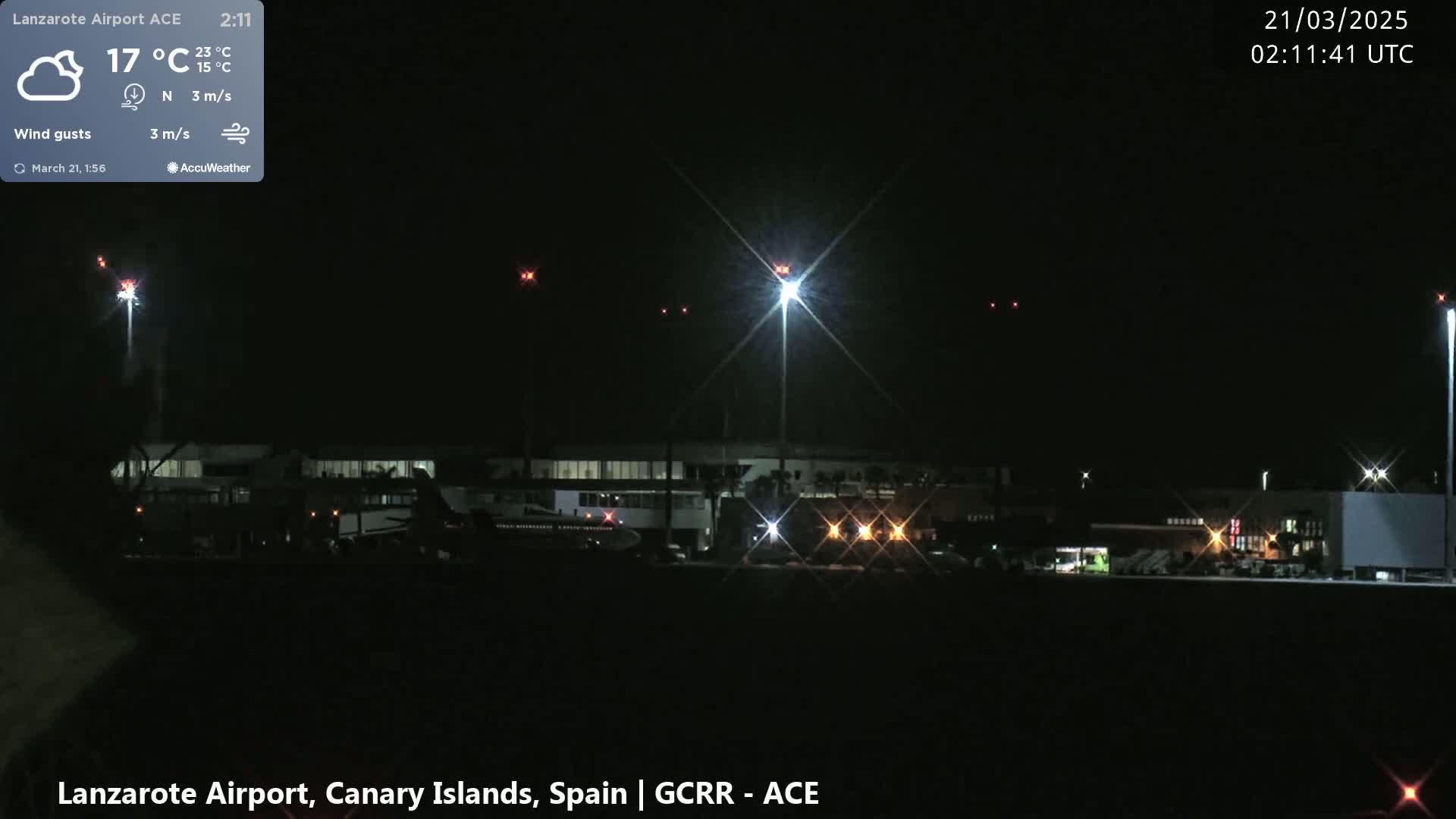 A nighttime view of an airport with bright lights illuminating the tarmac and buildings under a clear, dark sky.