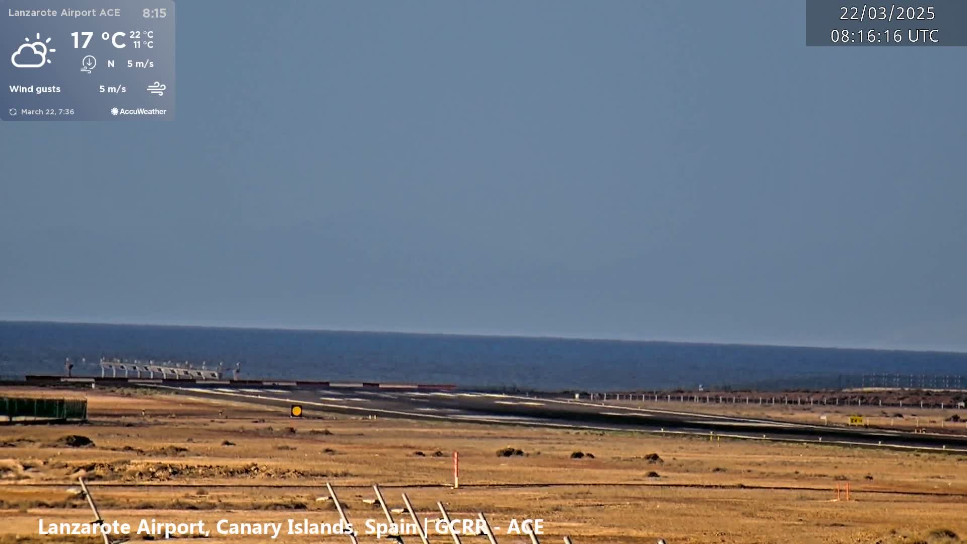 An airport runway stretches toward a calm ocean under a mostly clear sky.